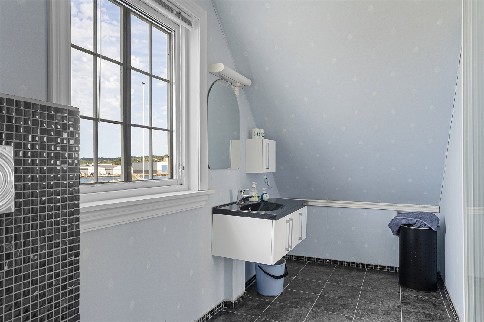 Tilleggsdel innredet som bad i loftsetasjen er innredet med dusjhjørne, baderomsinnredning med servant og speil, samt veggmontert toalett. Galleribilde