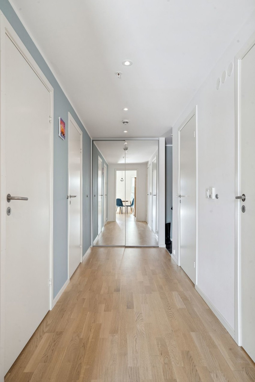 Gang, sett fra stue / kjøkken mot entre. Skyvedørsgarderobe med speil.