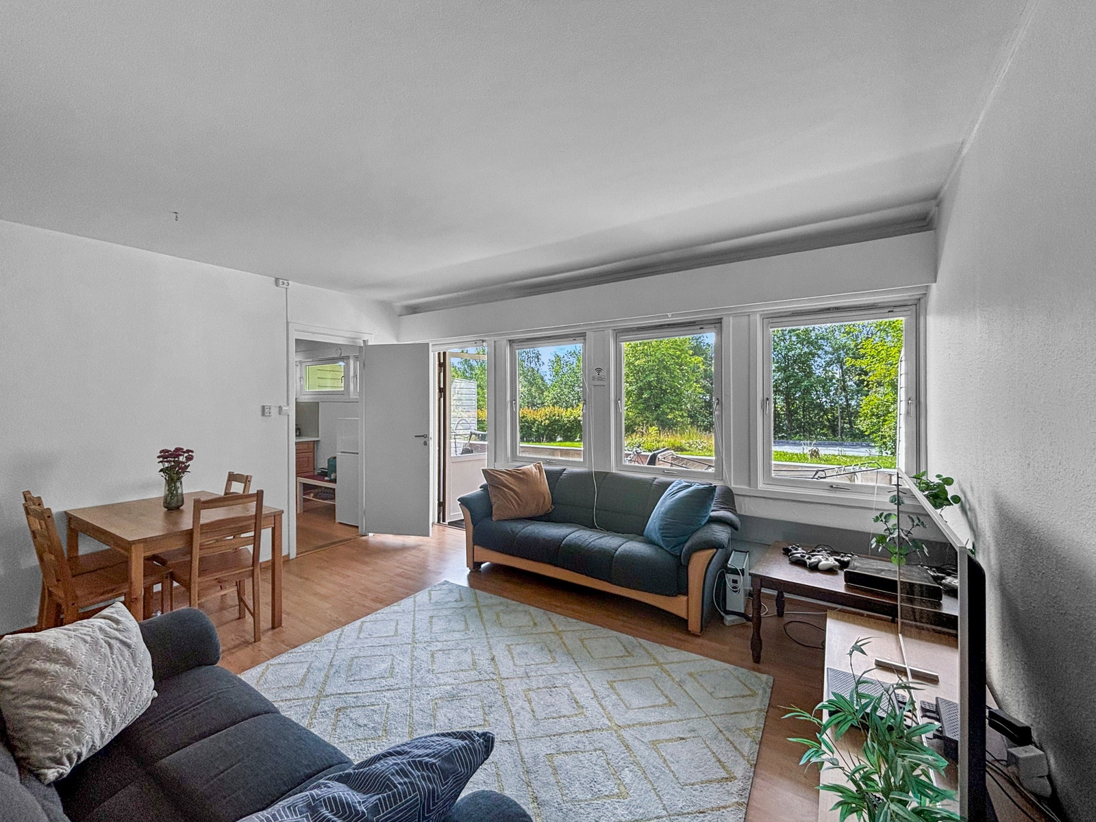 Stuen har en lys og åpen atmosfære, med flere vinduer som slipper inn godt med dagslys. Veggene er malt hvite, og rommet har plass til både sittegruppe og et mindre spisebord. Galleribilde