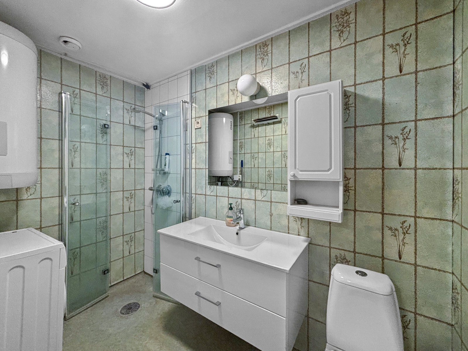 Badet har flislagte vegger og belegg på gulvet. Det er oppgradert med ny baderomsinnredning og dusjhjørne, samt opplegg for vaskemaskin. Galleribilde