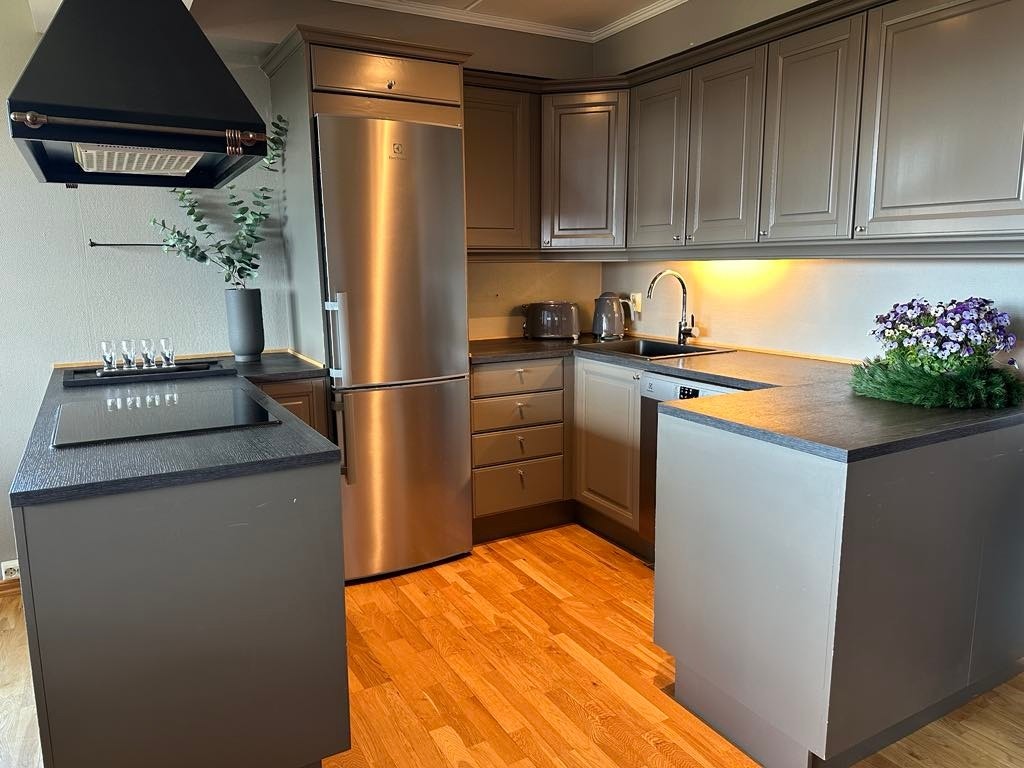 Kjøkkeninnredning med over- og underskap, og en øy mot stuen. Galleribilde