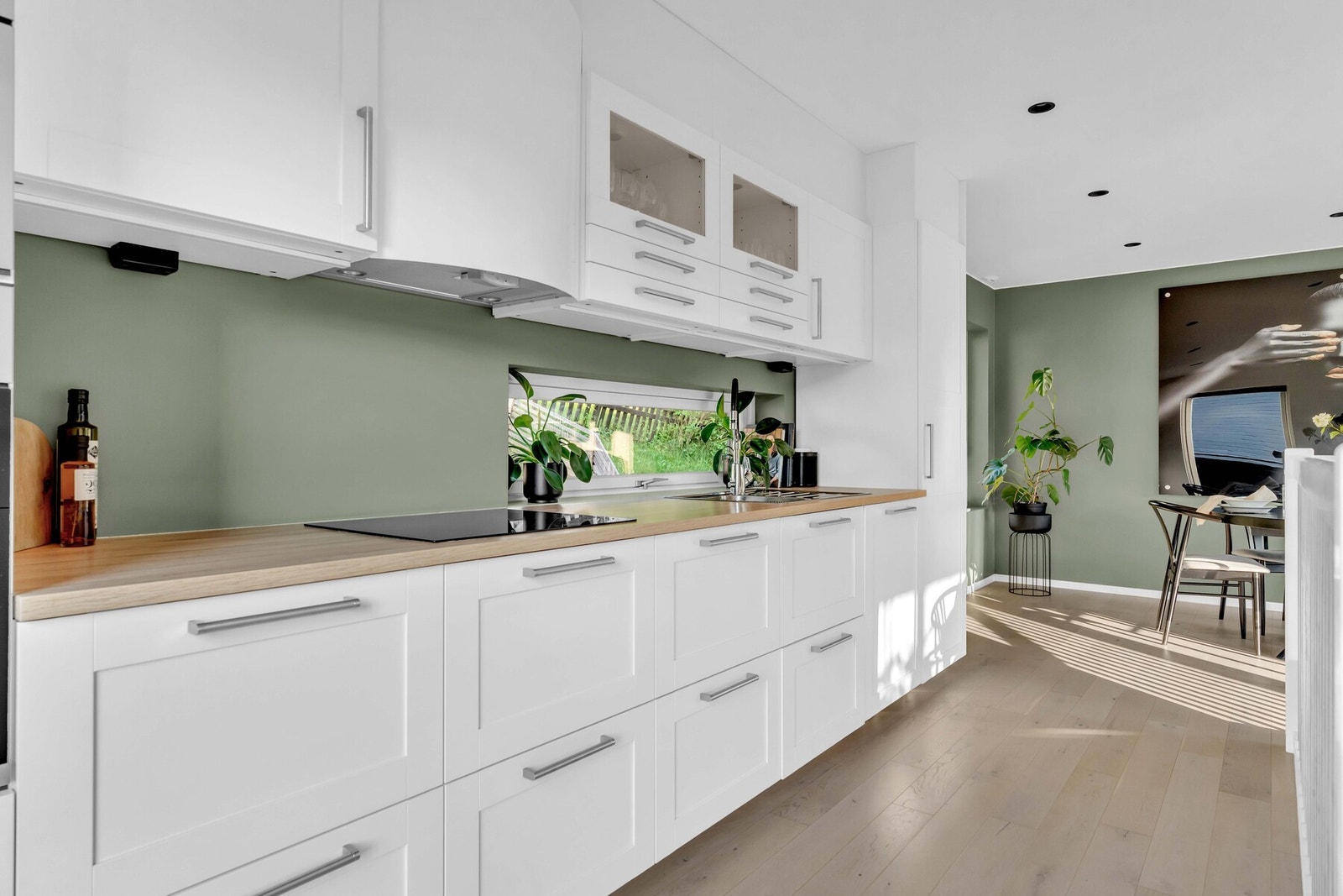 Innredningen har hvite, profilerte fronter og laminert benkeplate med nedfelt kum av rustfritt stål. Galleribilde