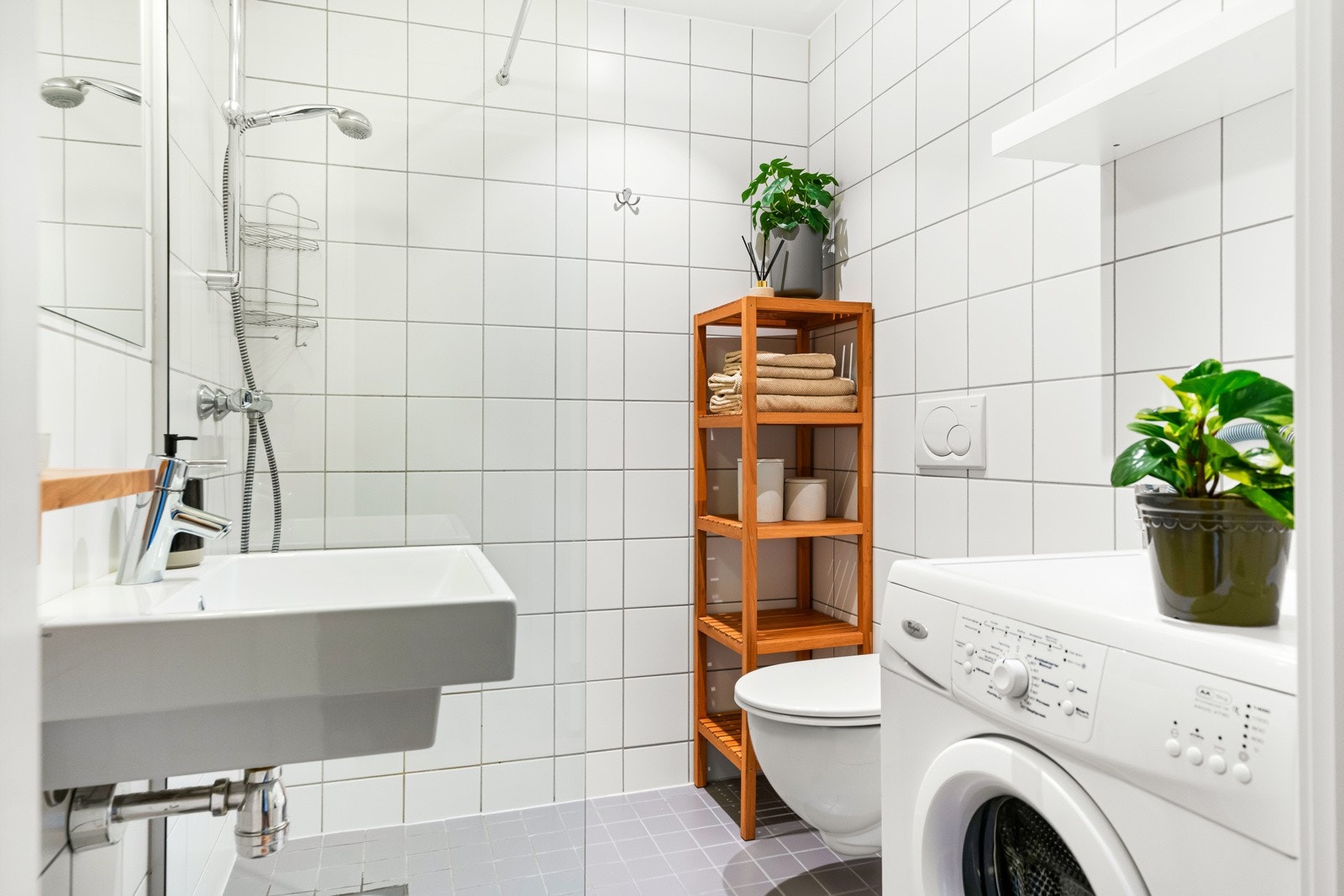 Tiltalende og lekkert baderom med lyse fliser. Opplegg for vaskemaskin. Galleribilde