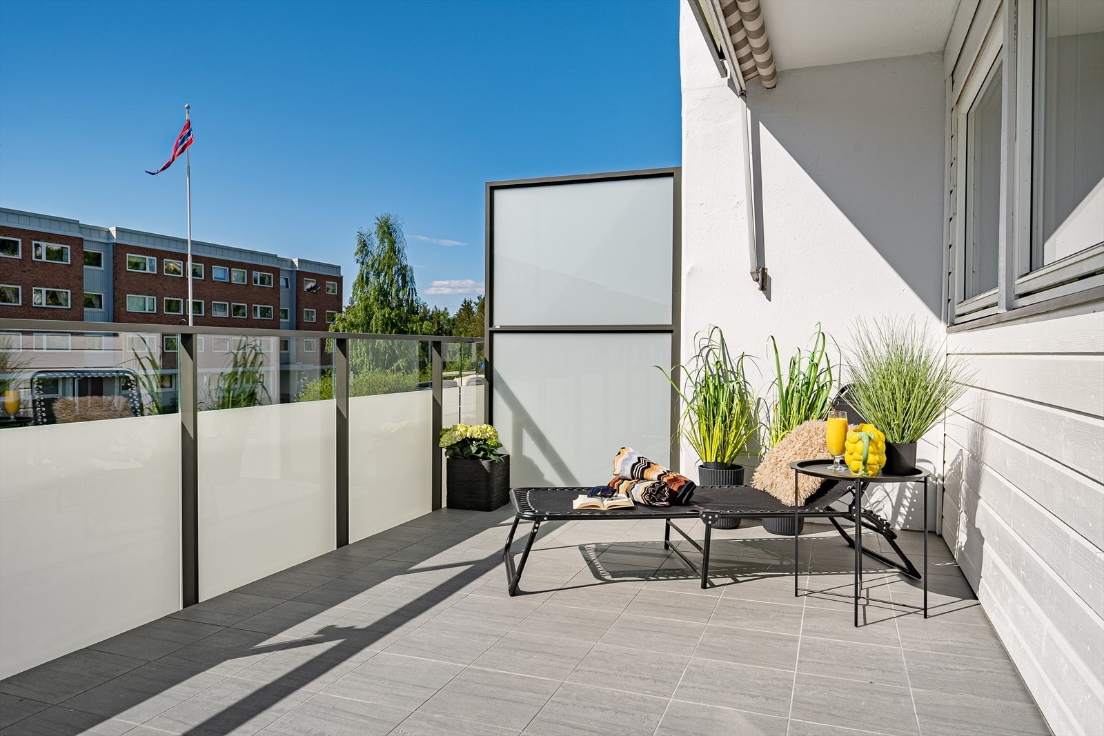 Leilighetens uteområde kan by på en svært generøs og solrik balkong med pene fliser og ny glassfasade. Det er montert markise som gir god solskjerming på varme dager. Galleribilde