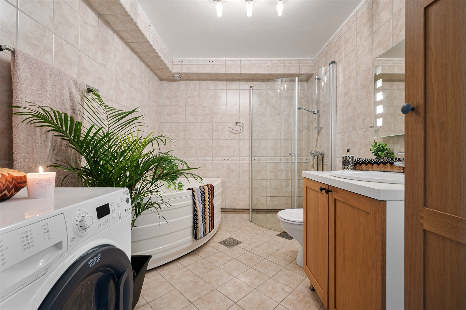 Flislagt baderom som gir hjemmeSPA-følelsen med både badekar og dusjhjørne. Innredning med høyskap og nedfelt servant i baderomsinnredning. Praktiske innfellbare dusjvegger i herdet glass, klosett og opplegg til vaskemaskin. Galleribilde