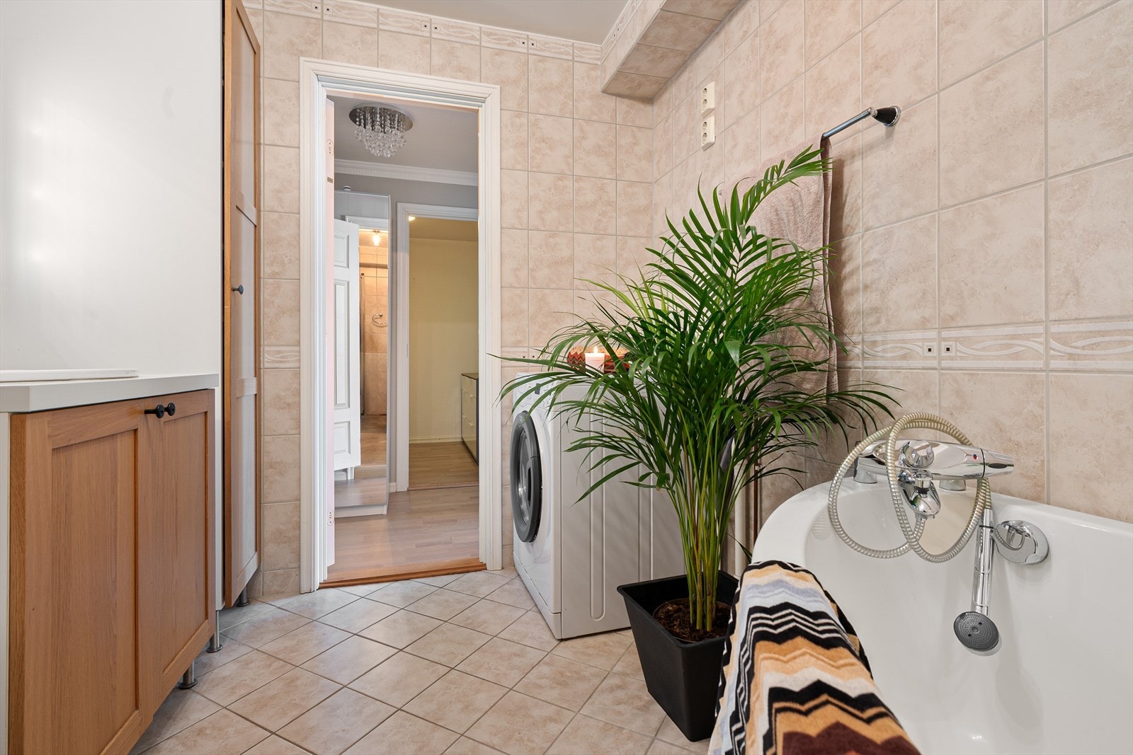 Badet har tidløse fliser med enkle pyntefliser på vegg og langs himling. Det er avsatt plass til vaskemaskin og tørketrommel i vaskesøyle. Galleribilde