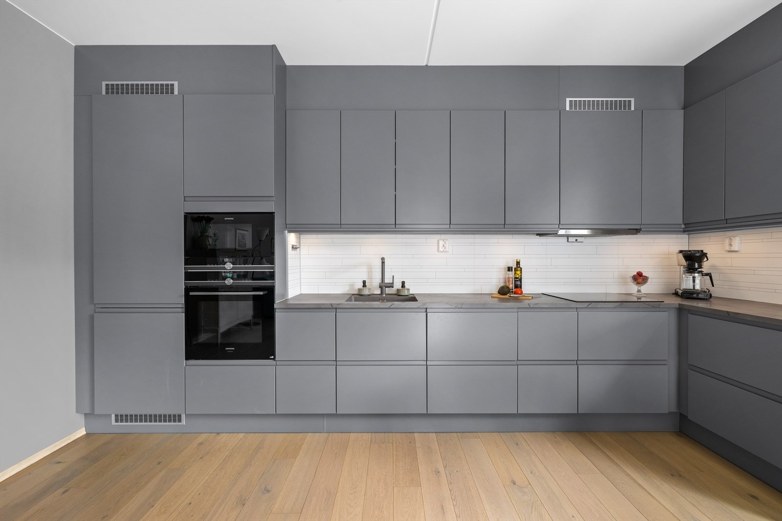 Det er et stilrent kjøkken fra HTH med integrerte hvitevarer og rikelig med skap - og benkeplass. Galleribilde