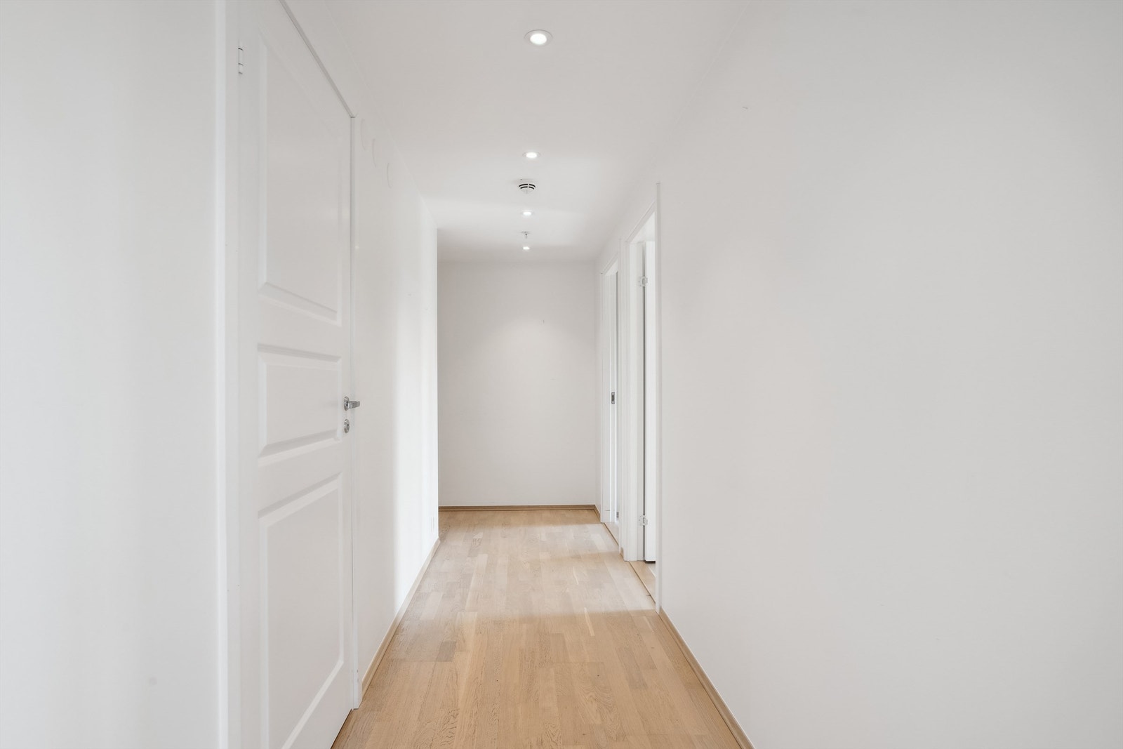 Lys og innbydende gang som binder sammen leilighetens ulike rom på en elegant måte. Galleribilde