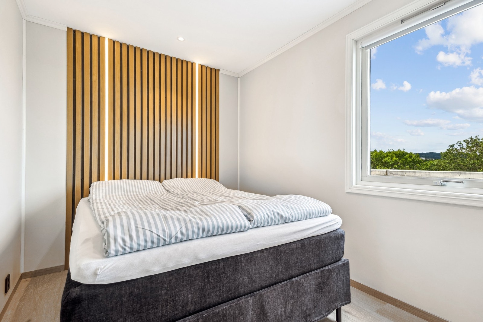 Romslig soverom på 10 kvm med moderne spilegavl bak sengen, stilfullt belyst med integrert LED-stripe - en detalj som skaper både atmosfære og særpreg. Galleribilde