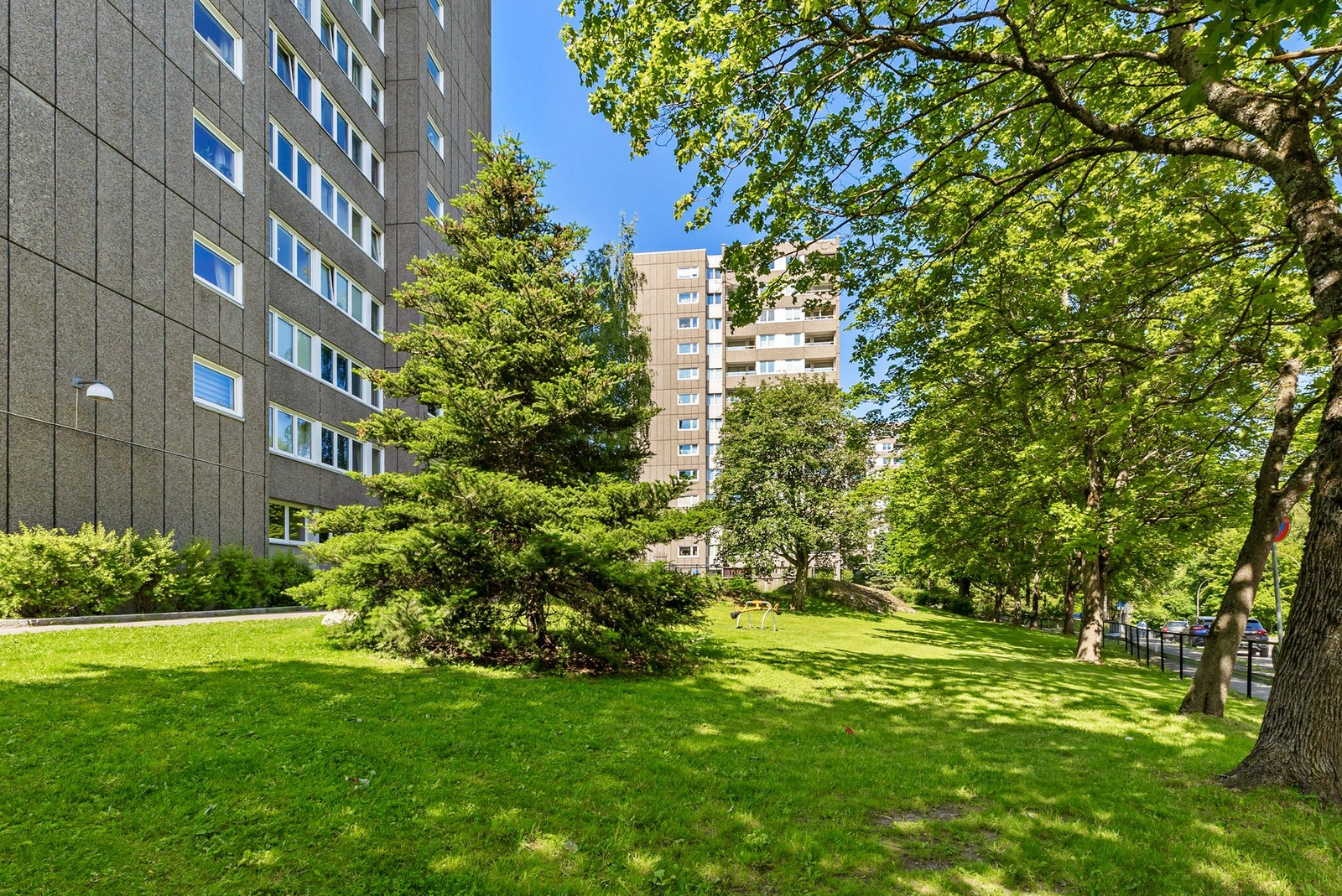 Leiligheten er omringet av store plenarealer med løv og vintergrønne trær som innbyr til bruk av området. Galleribilde