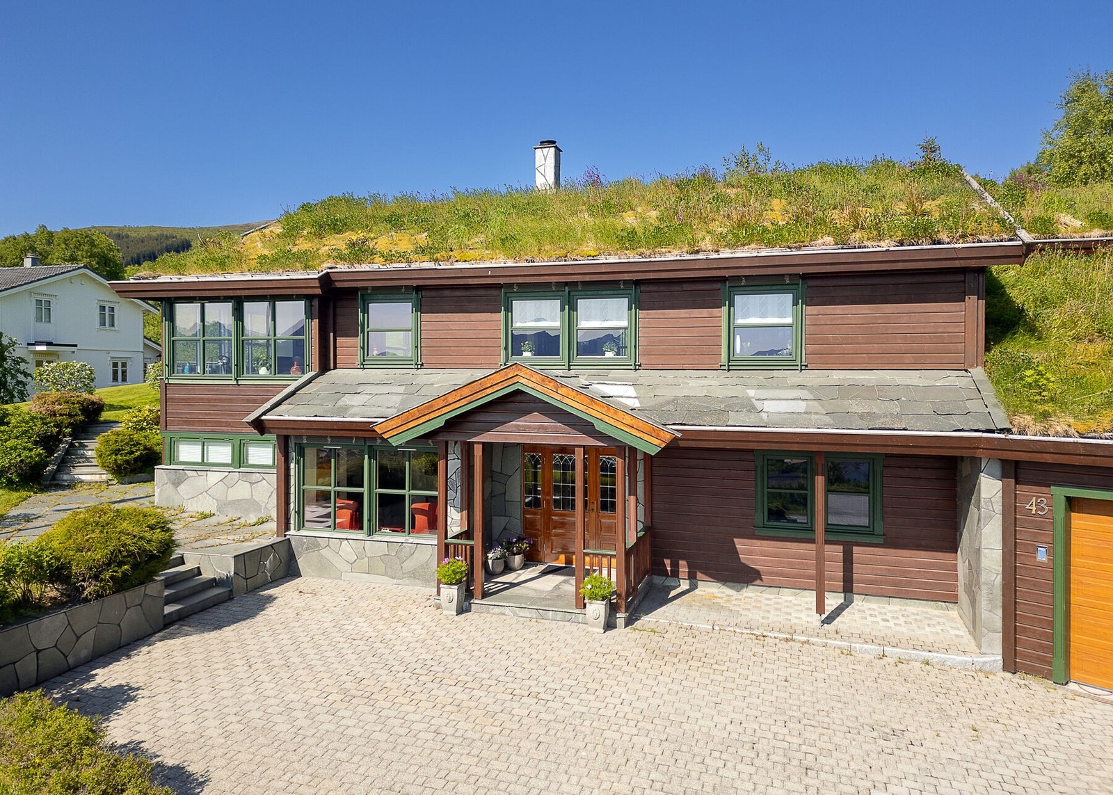 Eiendommen er flott opparbeidet med hageanlegg med plen, forstøtningsmurer, busker og trær. Det er også flaggstang på eiendommen. Galleribilde