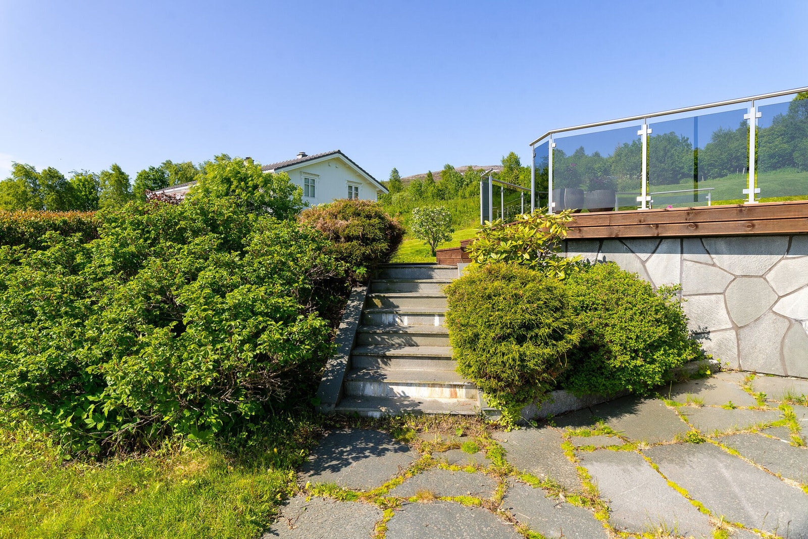 Uteområdet mot sør og øst. Trapp opp fra gårdsplass til hage og terrasse. Galleribilde