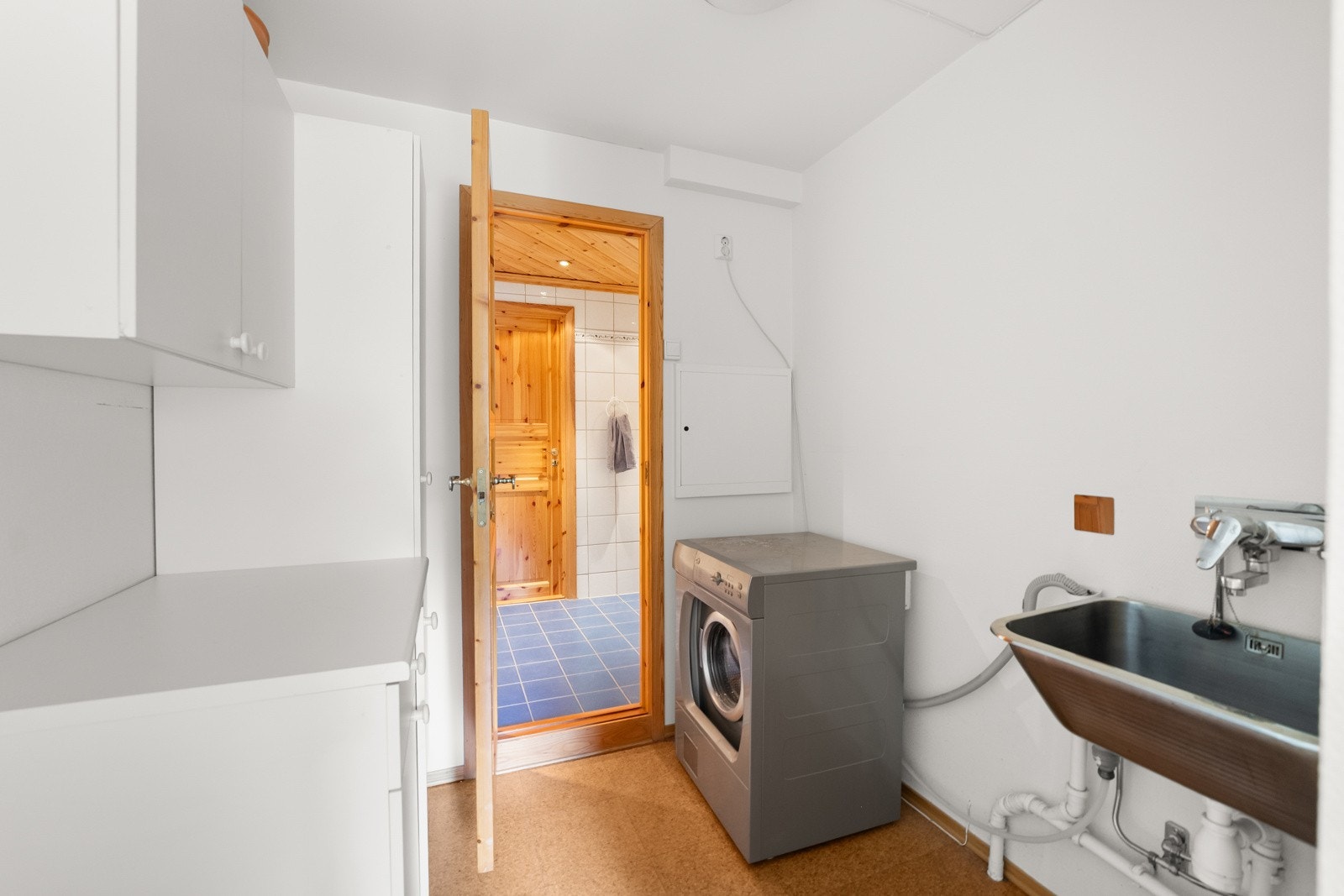 Tilliggende badet finner man en bod med utslagsvask, skapseksjoner og opplegg for vaskemaskin Galleribilde