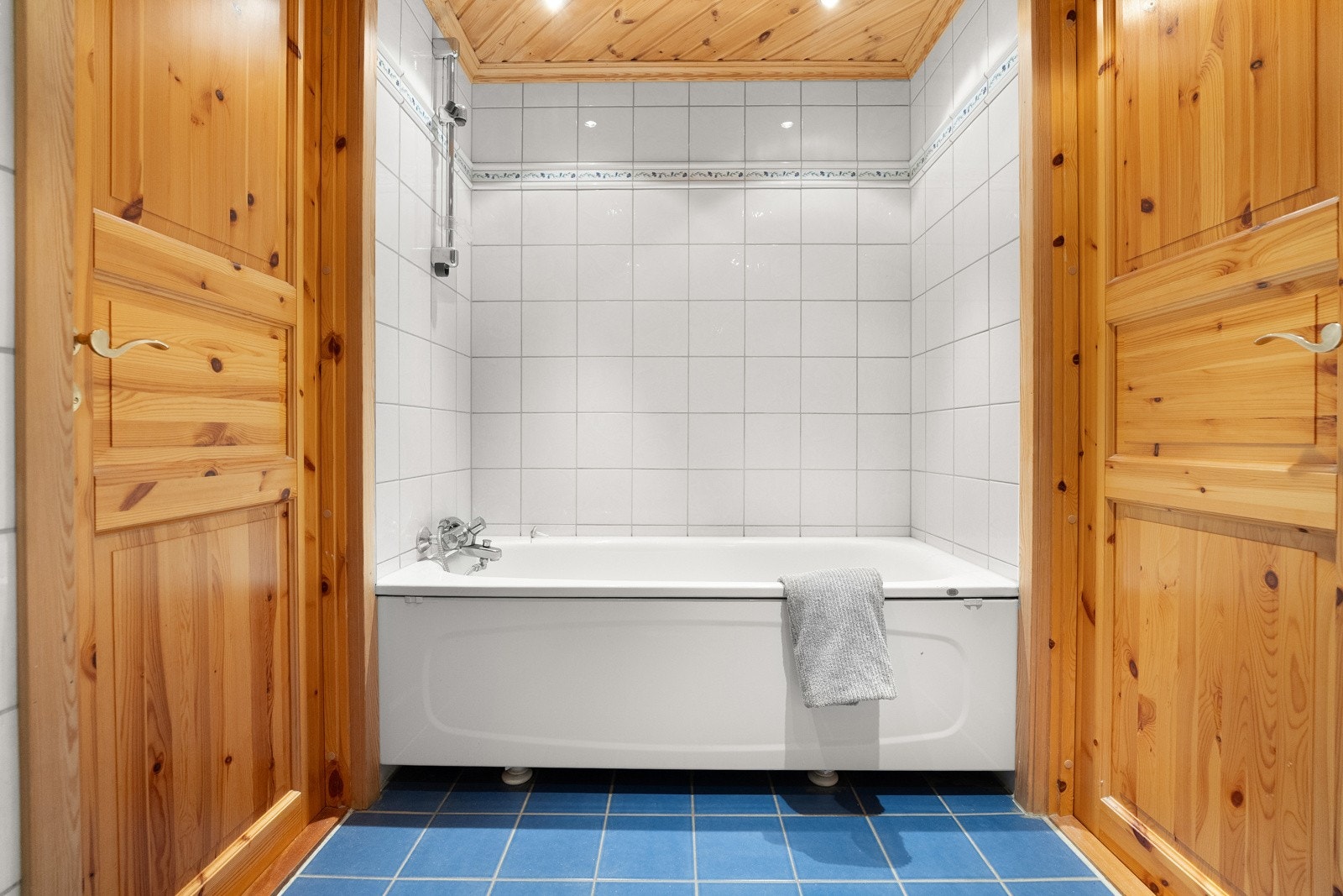 . Badet ved soverommet har hvite veggfliser og mørkeblå gulvfliser for en fin kontrast. Varme er lagt under gulvet, og badet har toalett, downlights og et badekar med dusjløsing Galleribilde