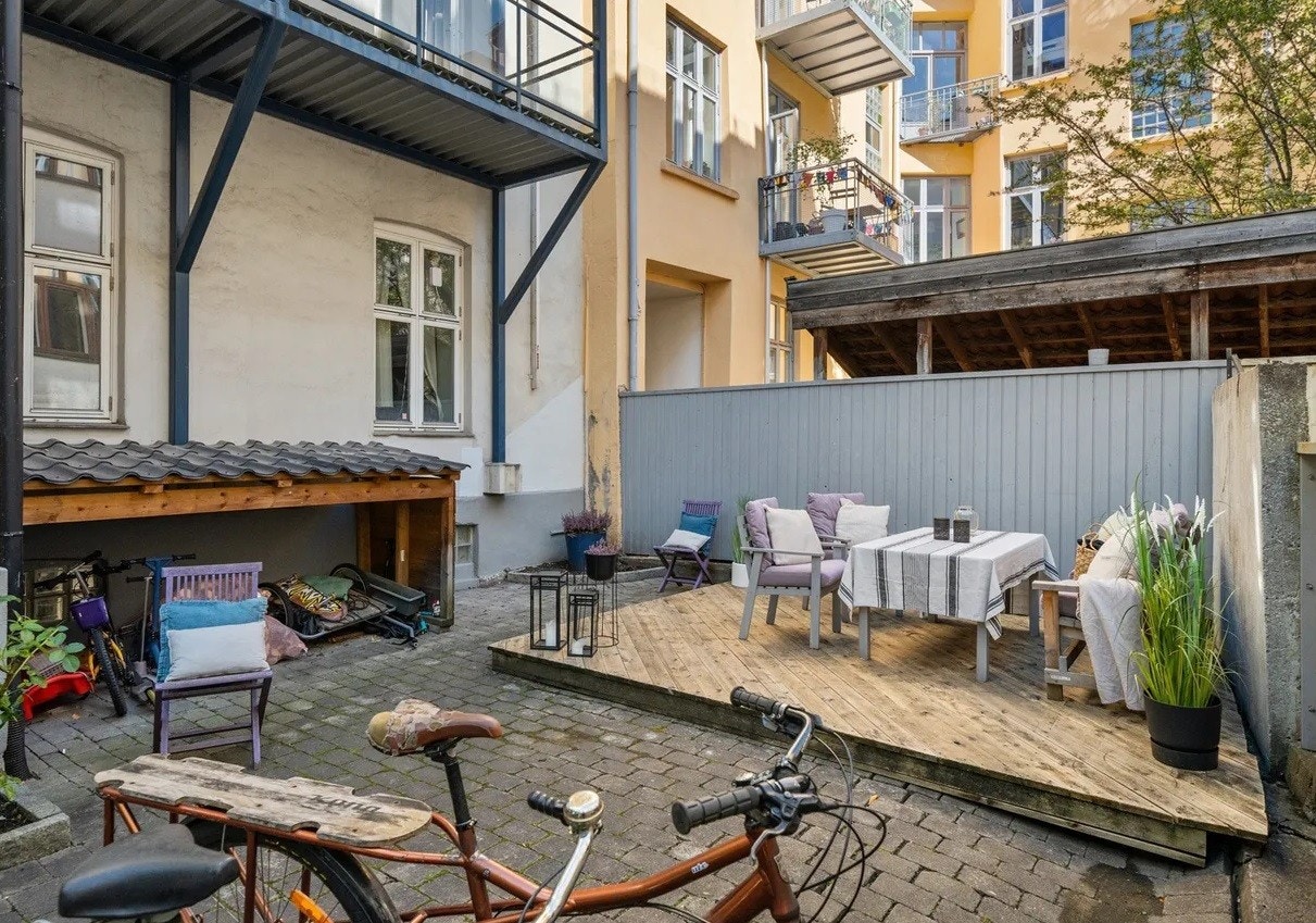 Flott opparbeidet bakgård med brostein, beplantning, sittegruppe, bod og sykkelparkering. Galleribilde