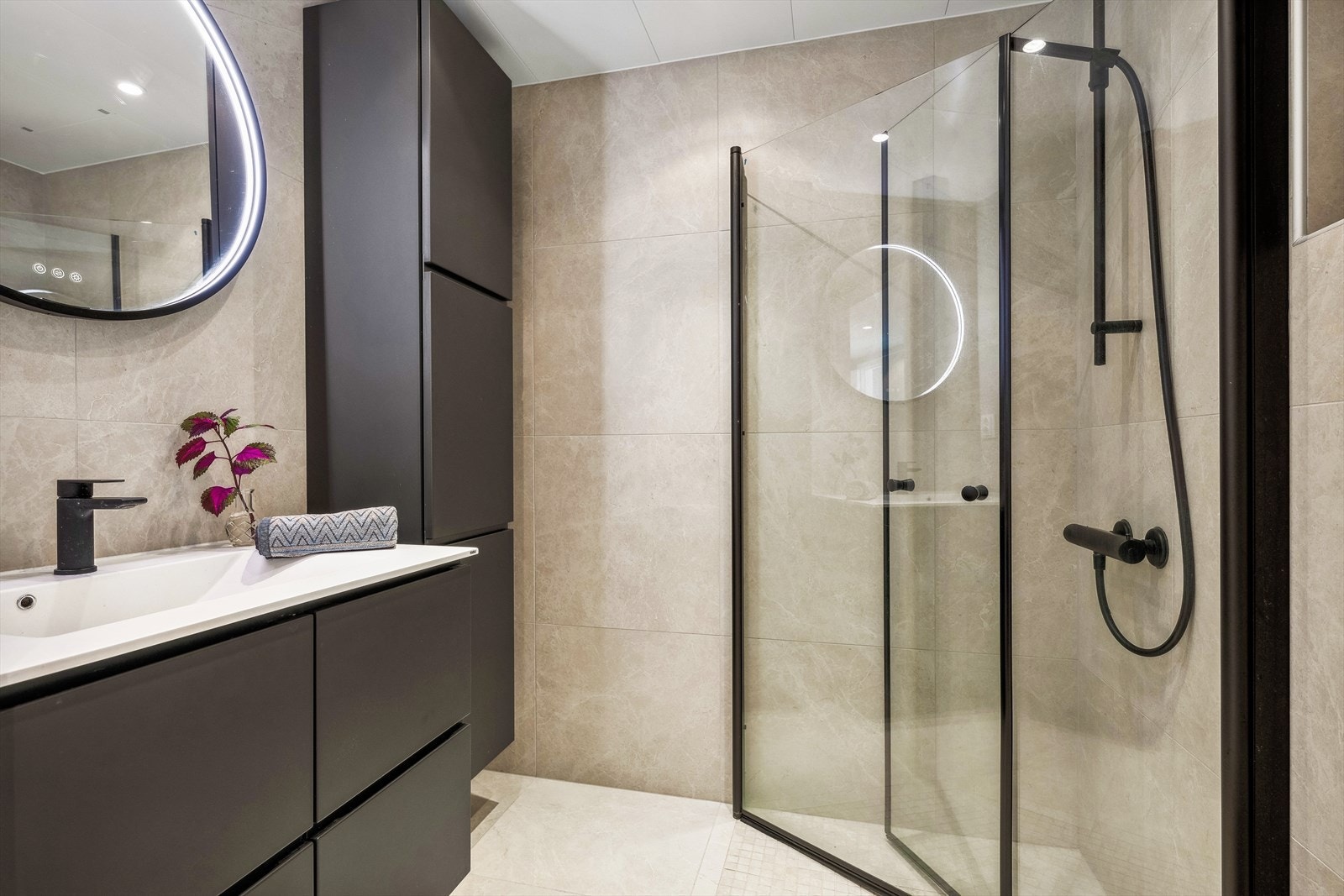 Leilighetens andre bad er innredet med vask i seksjon, speil med belysning, høyskap, dusj bak svingbare glassdører og vegghengt toalett. Galleribilde