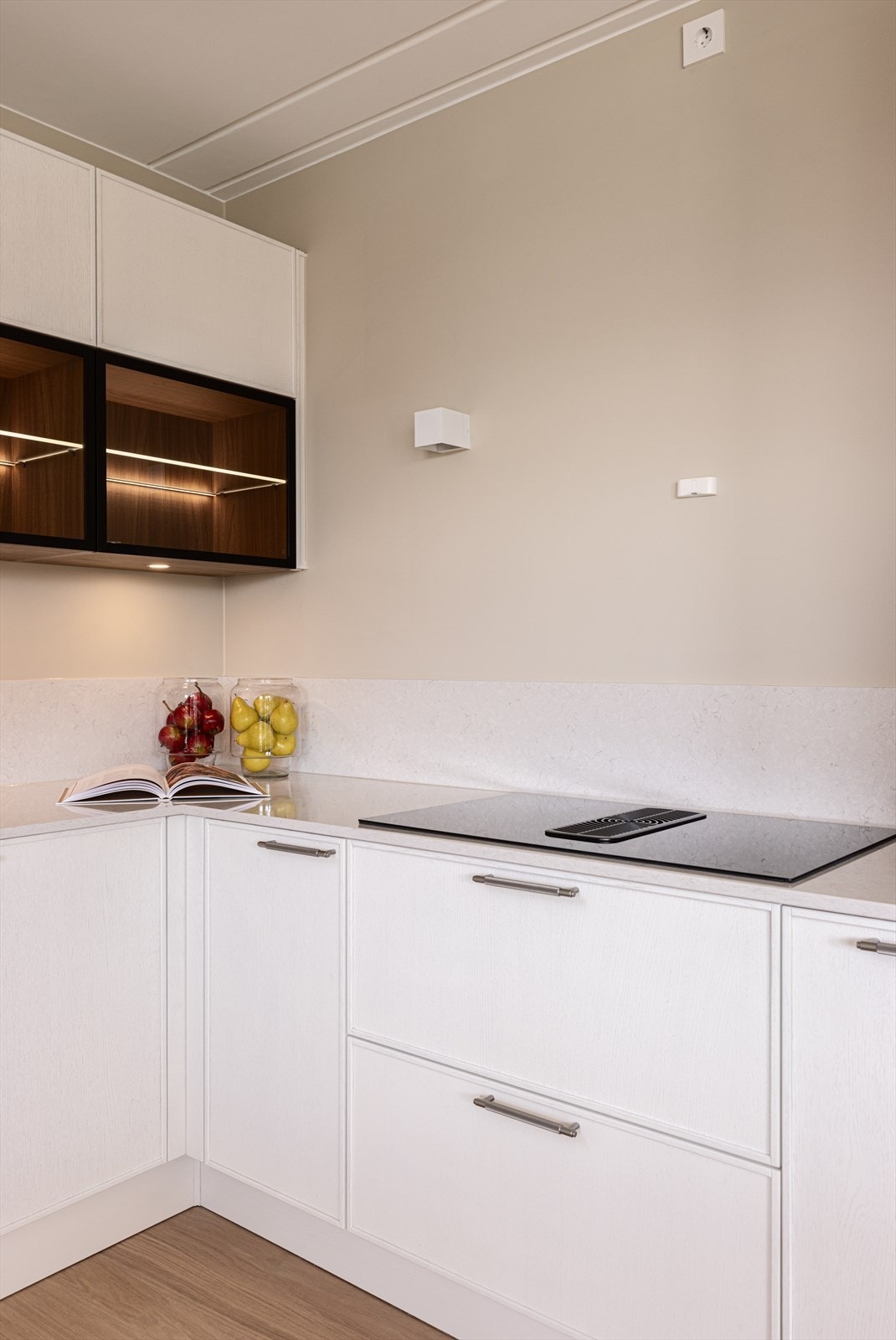 Silestone benk- og splashplater med induksjonstopp med benkventilator. Legg merke til dimbar belysning i overskap med fronter i sotet glass. Galleribilde