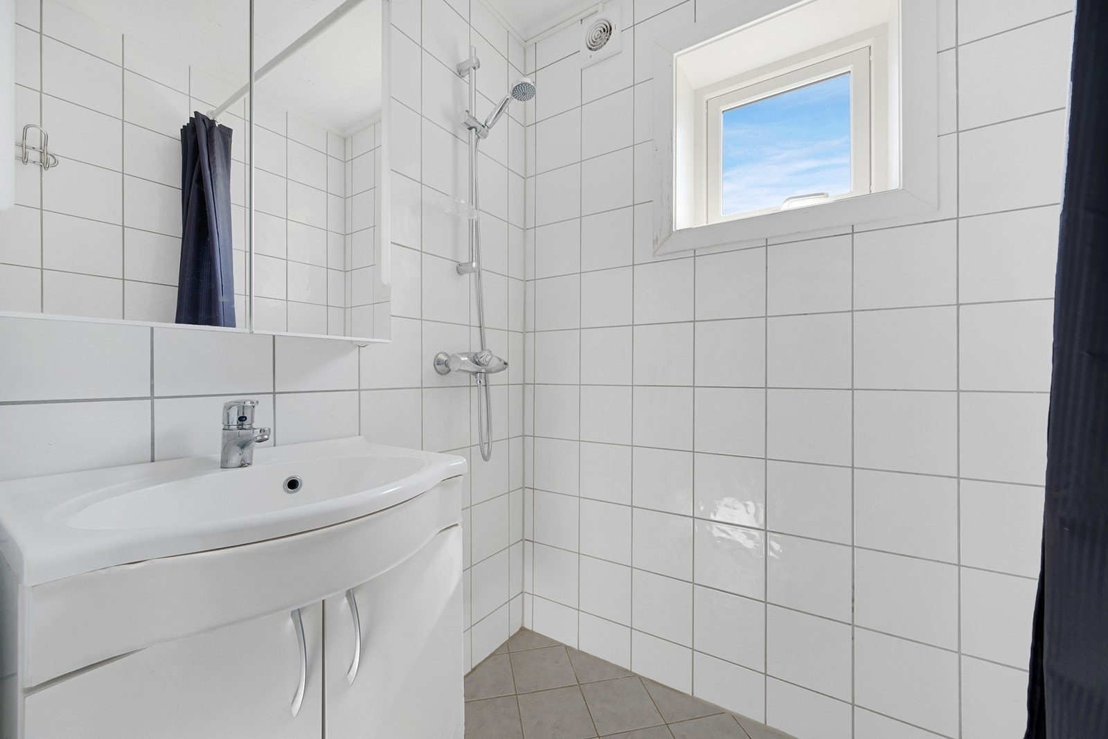 Videre har badet dusjsone med dusjforheng og opplegg for vaskemaskin og tørketrommel. Galleribilde