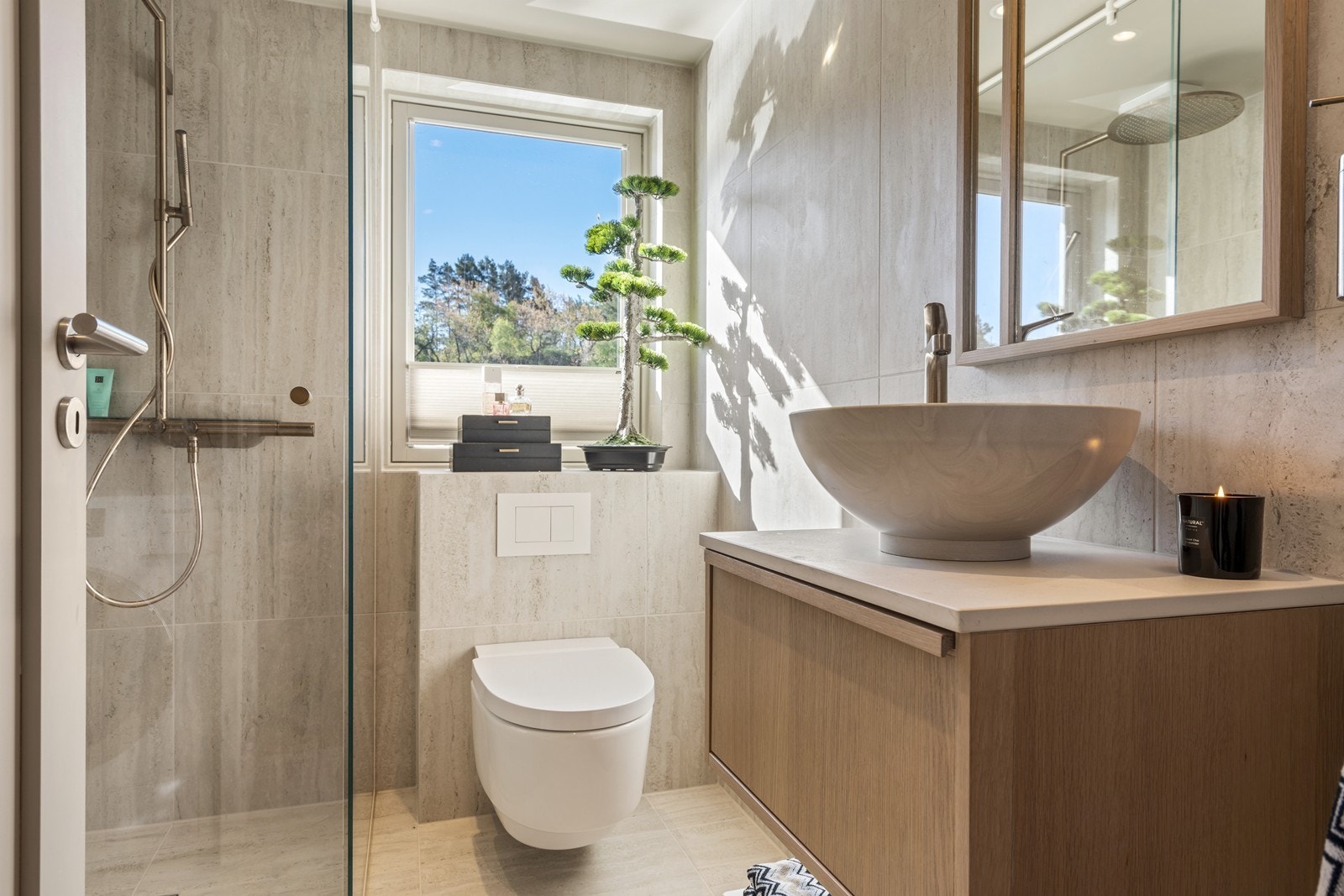 Påkostet og helfliset bad med vegghengt toalett, dusjhjørne og innredning med servant Galleribilde