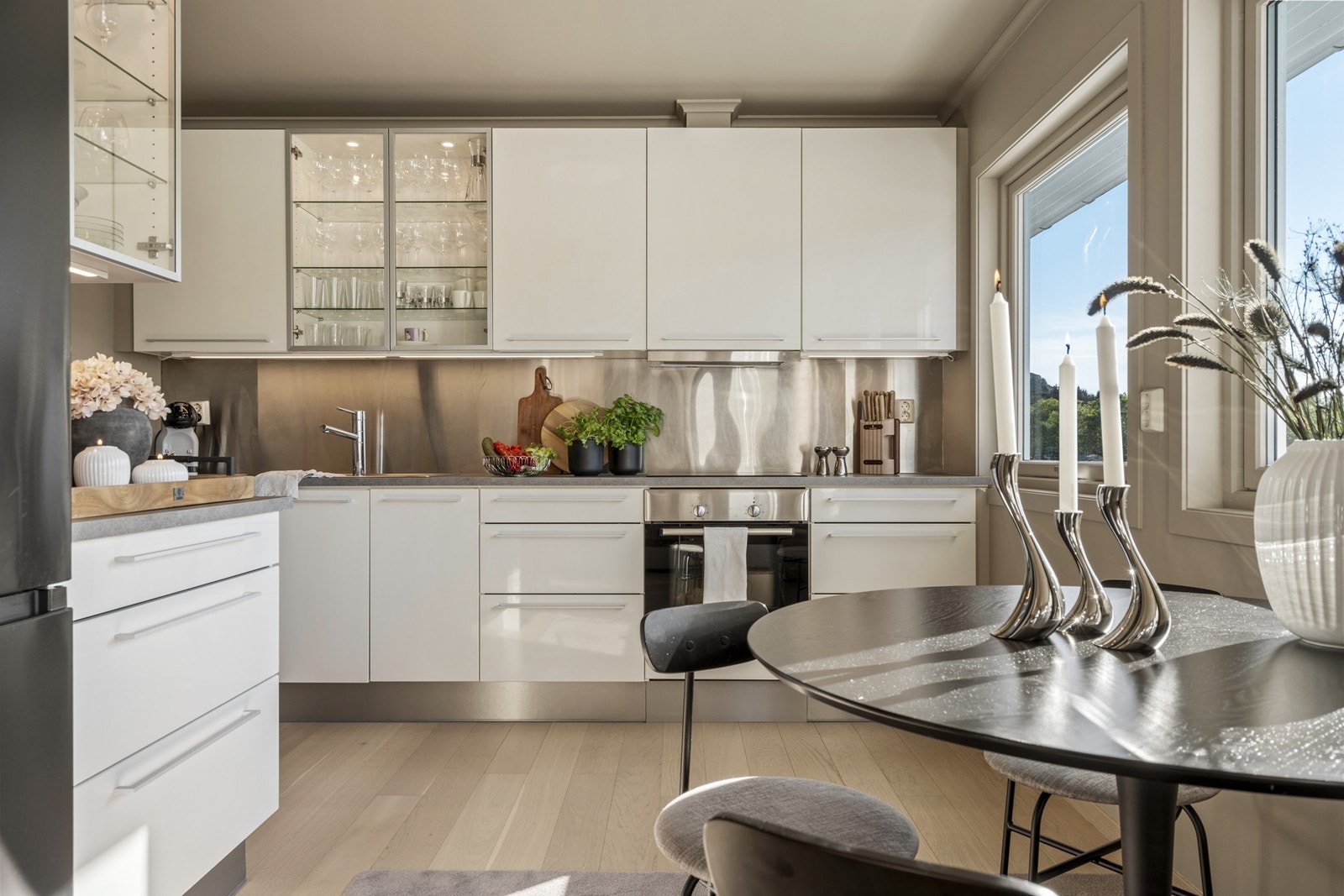 Delikat kjøkken med hvit innredning og mørk benkeplate. Integrerte hvitevarer. Galleribilde