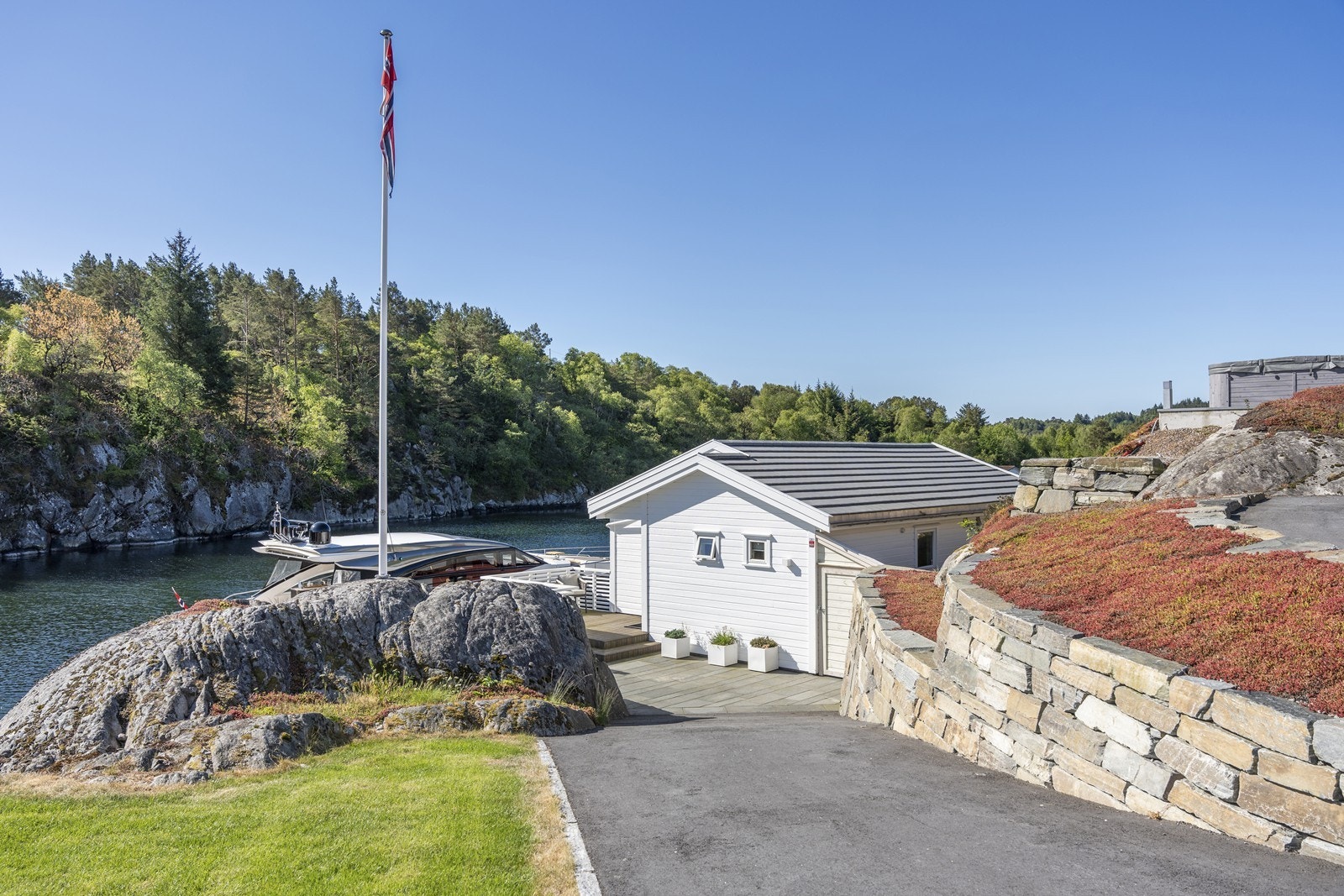 Tomten er påkostet og nydelig opparbeidet med natursteinsmurer, bedd, gressplen og asfaltert gårdsrom/veier Galleribilde