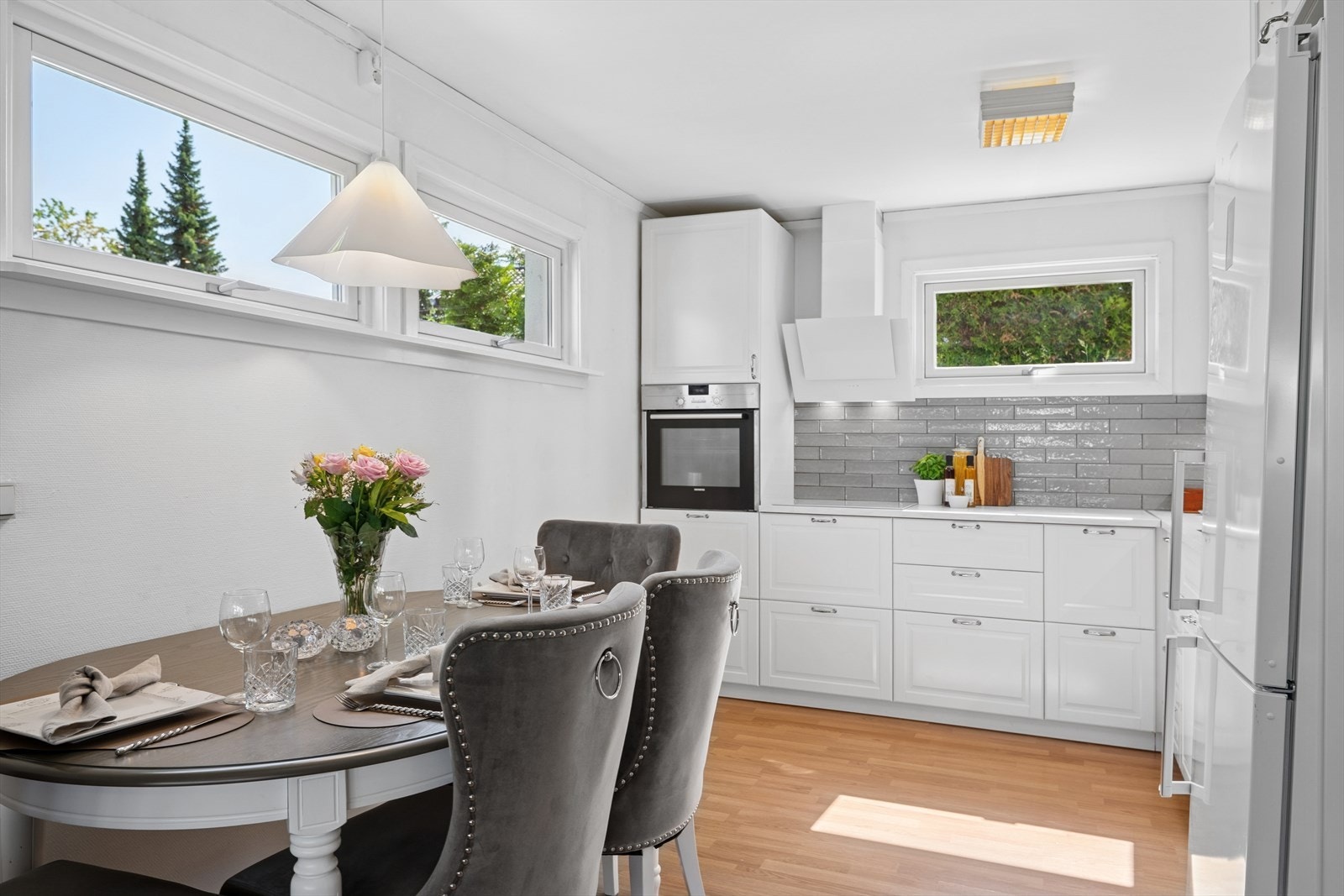 Videre er kjøkkenet utstyrt med integrerte hvitevarer som oppvaskmaskin, stekeovn og koketopp, samt ventilator og benkebelysning. Veggfeltet over benken har glaserte, grå fliser som står godt til resten av interiøret. Galleribilde