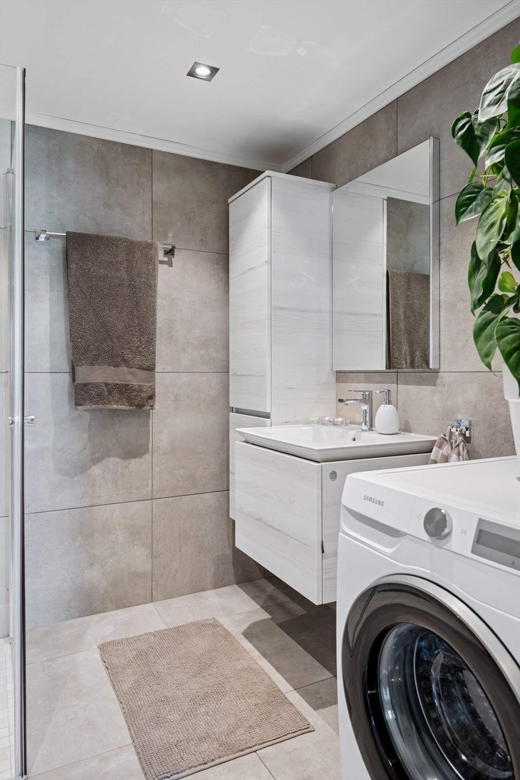 Baderomsinnredningen har lyse, finerte fronter og består av en toppmontert servant på en skuffeløsning, et høyskap og speil. Det er opplegg for vask og tørk Galleribilde