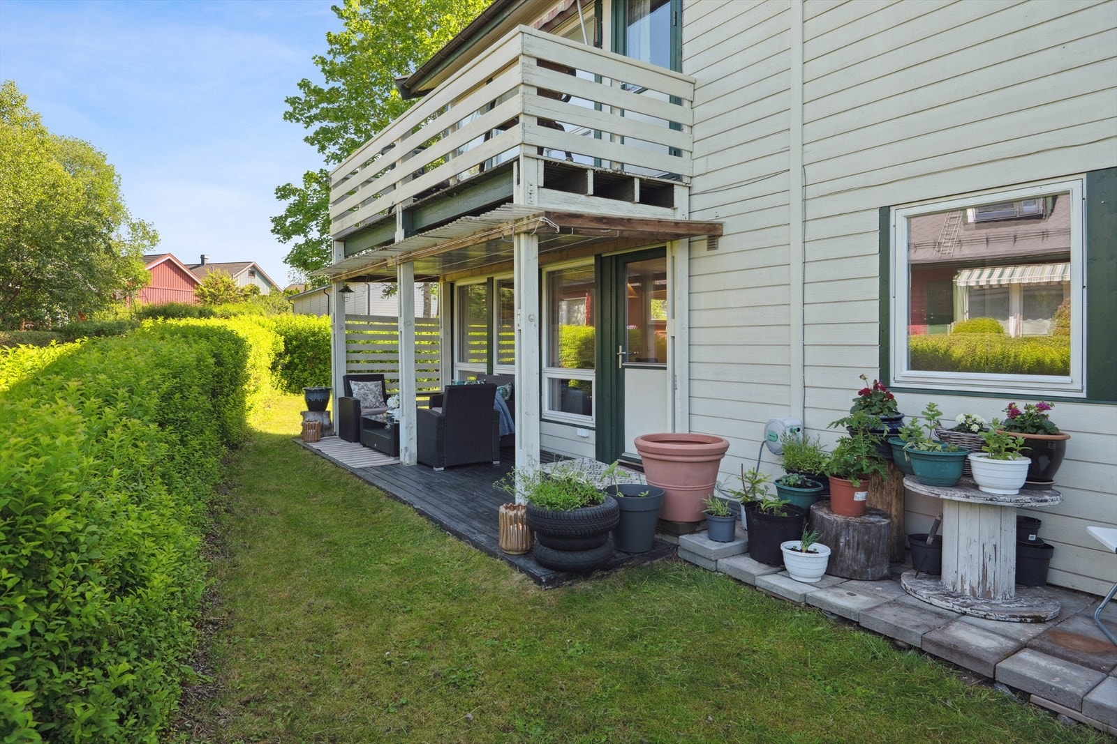 Terrassen sett fra en annen vinkel en lun uteplass med grønn ramme av hekk og gressplen. Perfekt for morgenkaffen eller hyggelige sammenkomster. Galleribilde