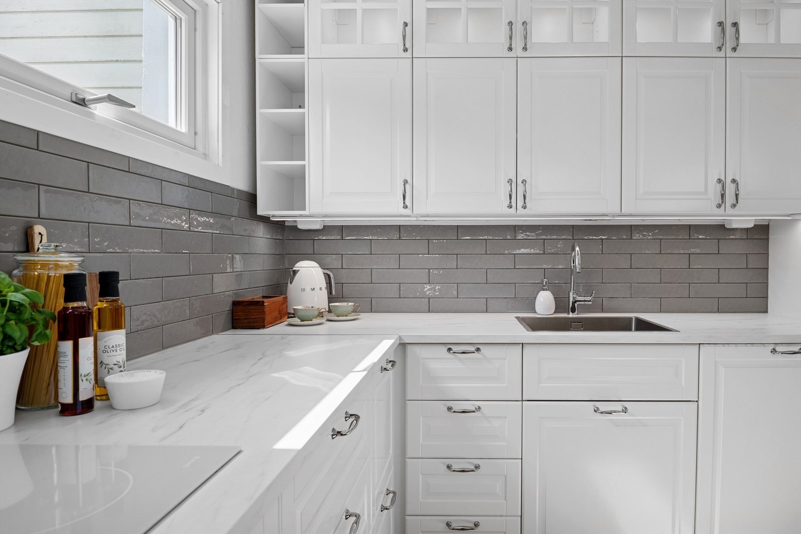 Innredningen har hvite, profilerte fronter, vitrineskap og hvit laminatbenkeplate med nedfelt kum i stål. Galleribilde