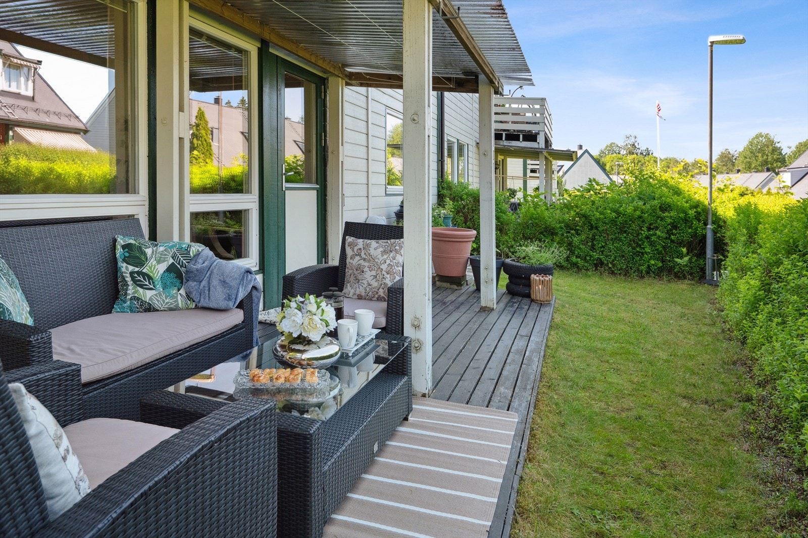 Fra stuen er det utgang til overbygget, terrasse på ca. 12 kvm. Rundt terrassen er det en koselig hage med gressplen, omkranset av hekk. Det er utekran med hageslange på veggen ved terrassen. Galleribilde