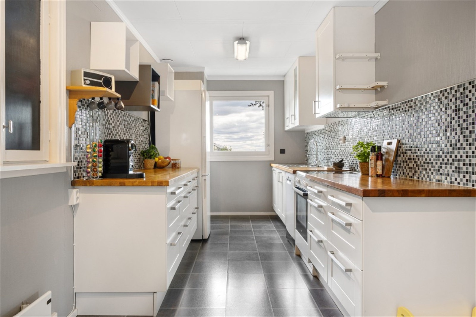 Lyst og koselig kjøkken. Innredning med lyse profilerte fronter. Heltre benkeplate og plass for frittstående hvitevarer Galleribilde