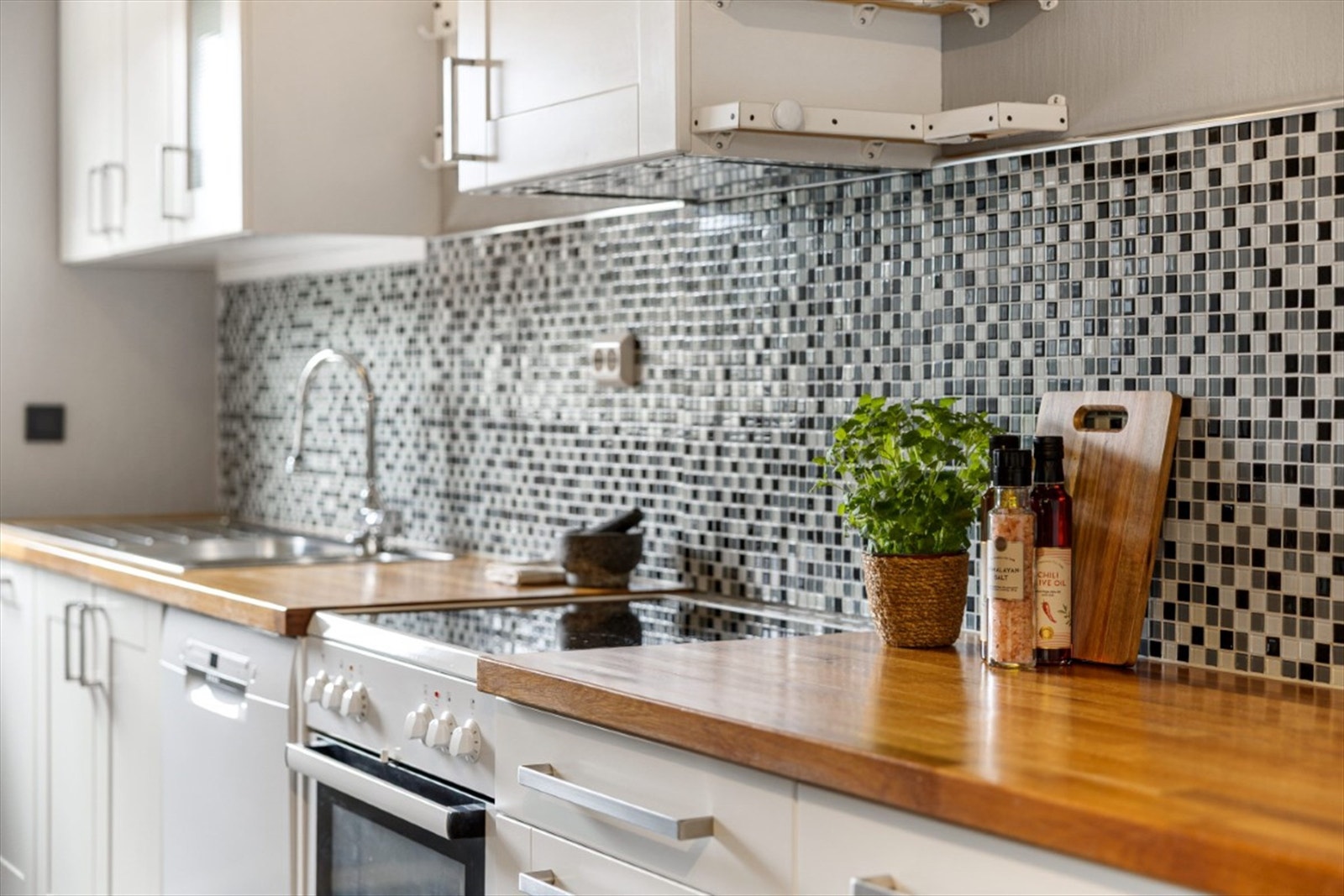 Benkeplate i heltre og mosaikkfliser gir kjøkkenet et innbydende og stilrent uttrykk. Galleribilde