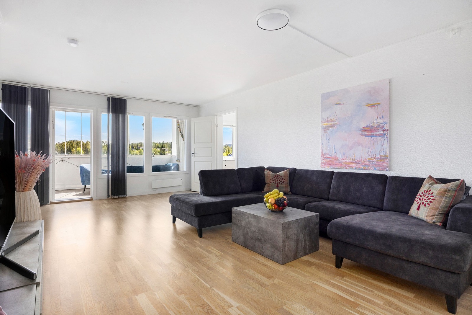 Romslig stue med store vindusflater og utgang til innglasset balkong. Galleribilde