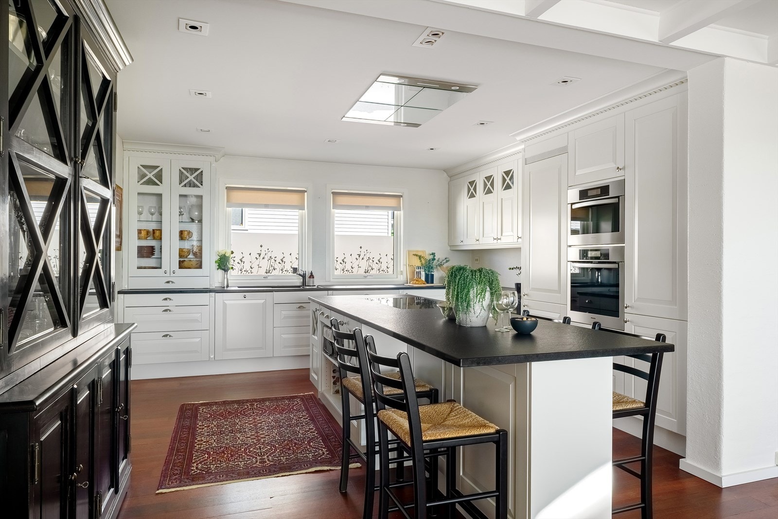 Et romslig kjøkken i lys og moderne stil, med profilerte fronter og stilren steinbenkeplate. Galleribilde