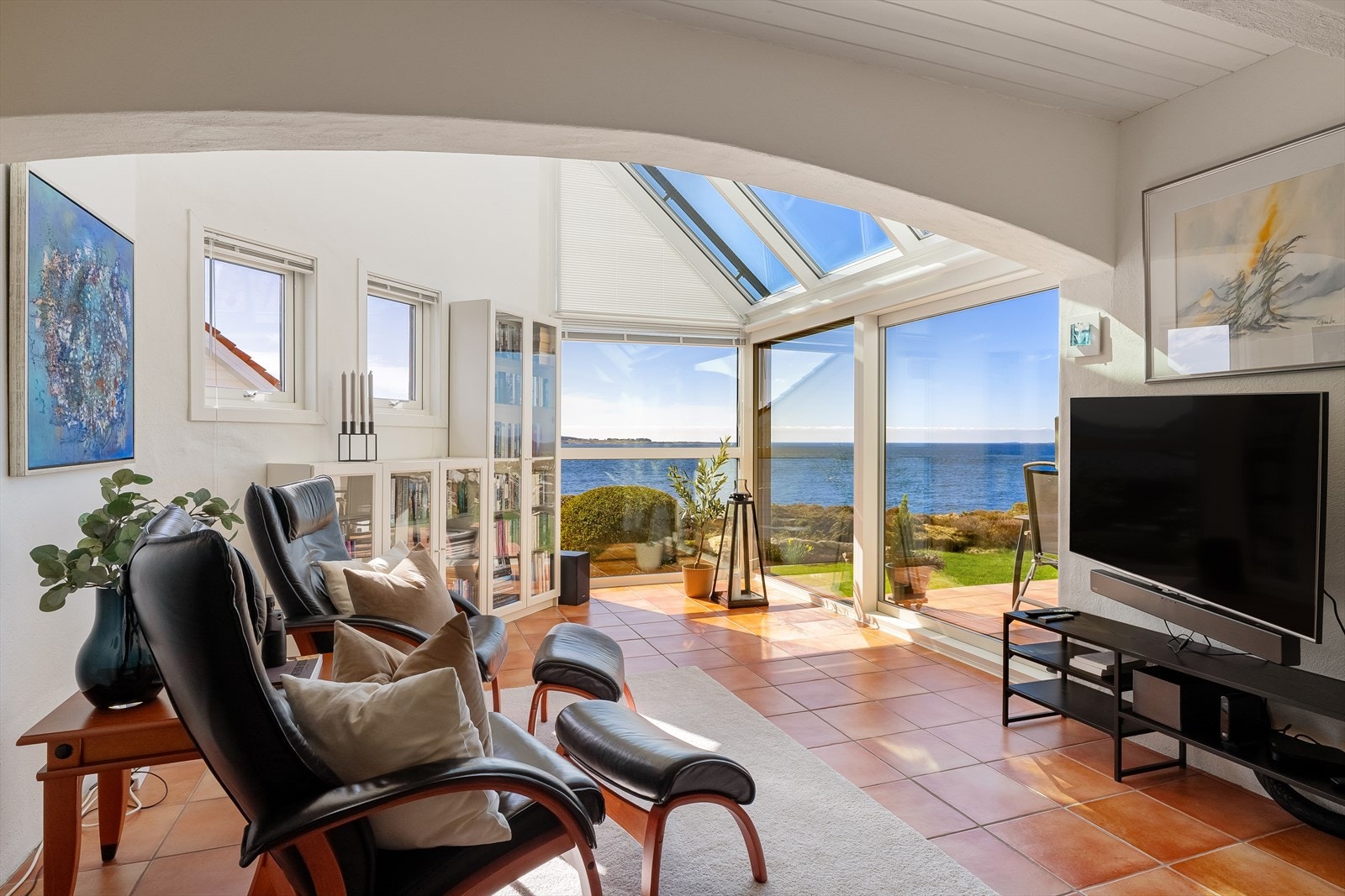 Fra hagestuen er det skyvedører ut til en pent opparbeidet terrasse med flislagt gulv. Herfra kan du nyte en spektakulær utsikt over havet og omgivelsene Galleribilde