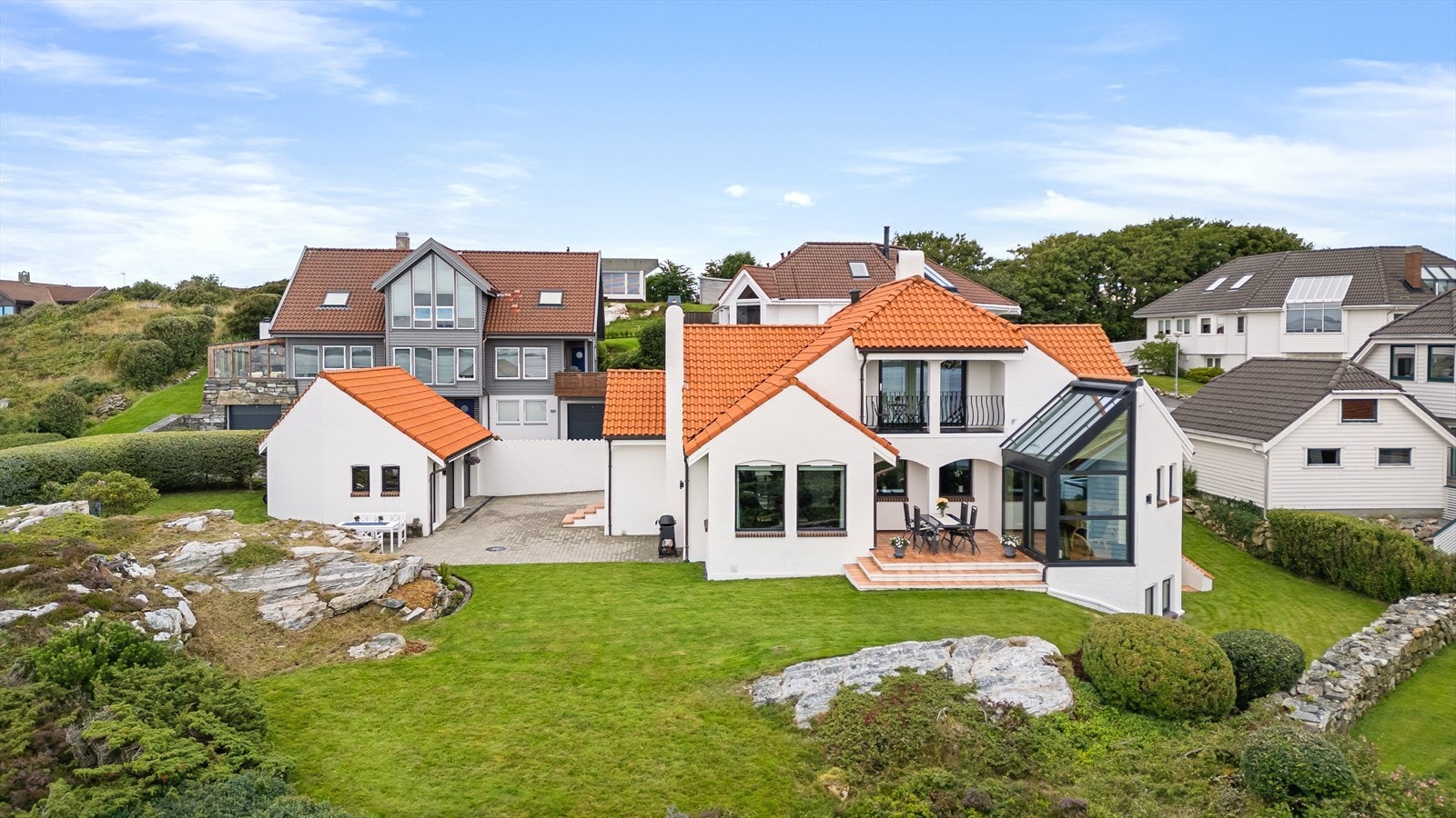 Tomten er vakkert opparbeidet med et innbydende uteområde som inkluderer flere koselige sitteplasser, velstelte grøntarealer og et romslig gårdsrom belagt med belegningsstein. Galleribilde