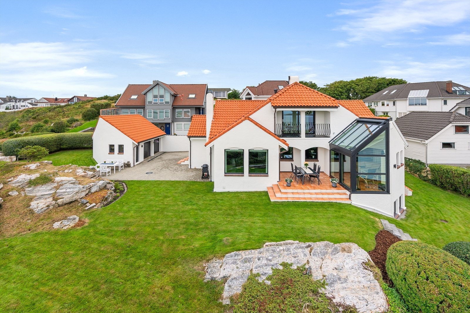 Tomten er vakkert opparbeidet med et innbydende uteområde som inkluderer flere koselige sitteplasser, velstelte grøntarealer og et romslig gårdsrom belagt med belegningsstein Galleribilde