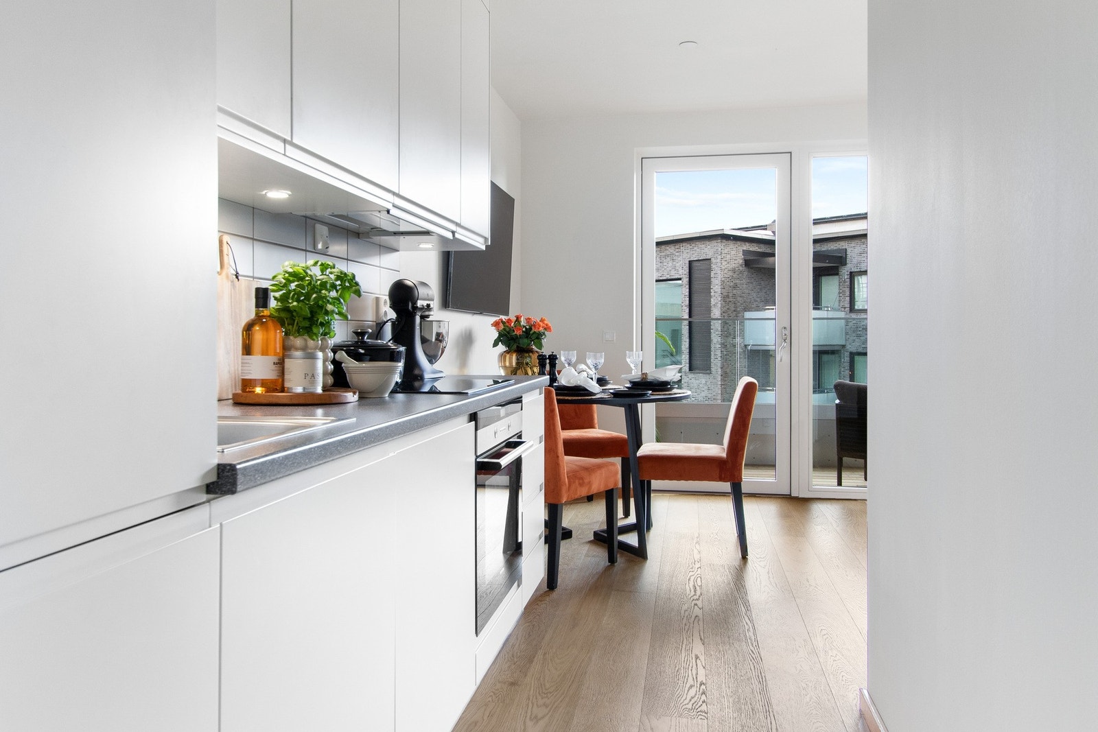 Selve kjøkkeninnredningen er bygget langs én vegg, med takoppforeden skap og slette, strømlinjeformede fronter som går i ett med veggfargen. Galleribilde