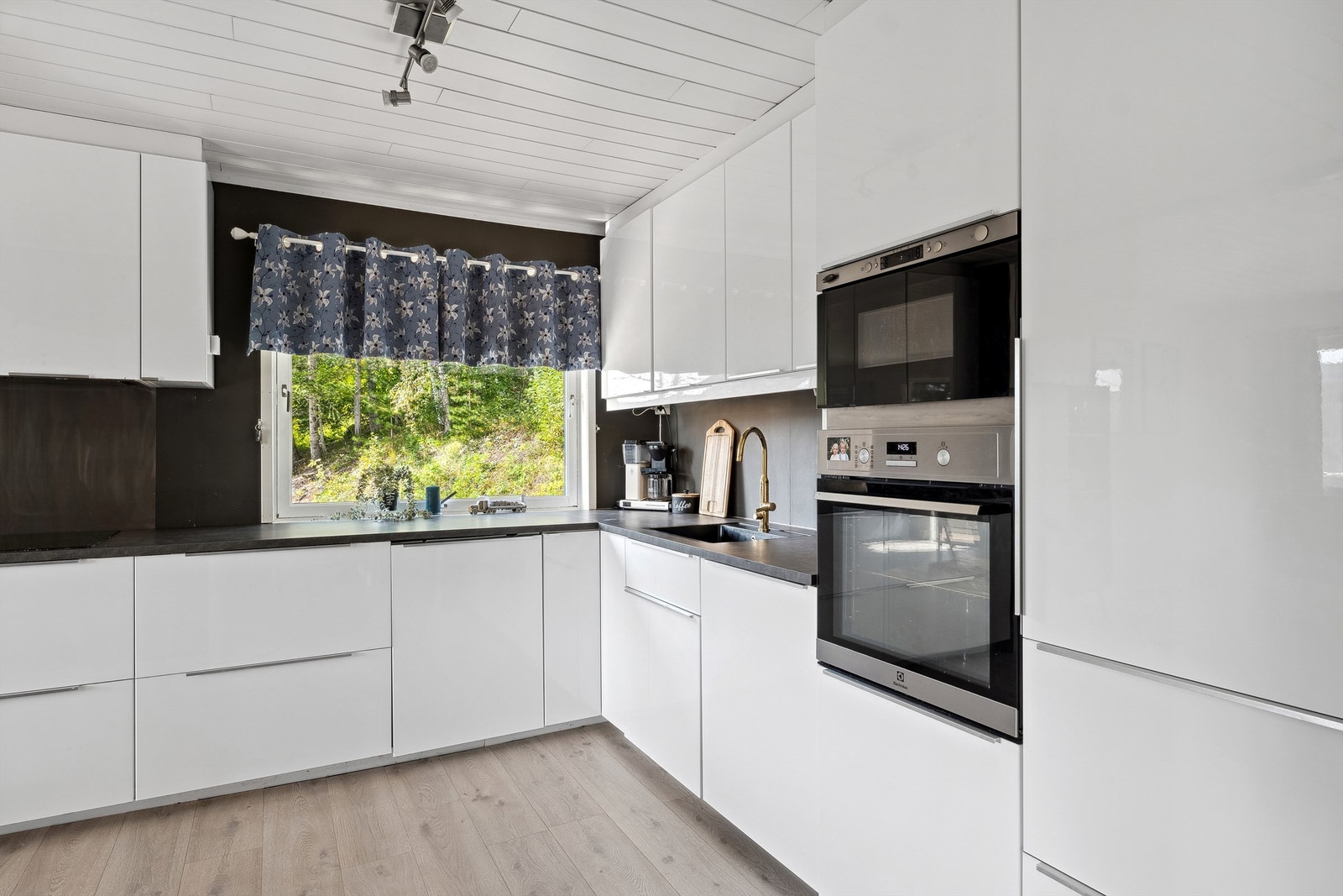 Kjøkkenet har Ikea innredning i hvit høyglans og med integrerte hvitevarer, blant annet med stekeovn og mikro i høyskap. Galleribilde