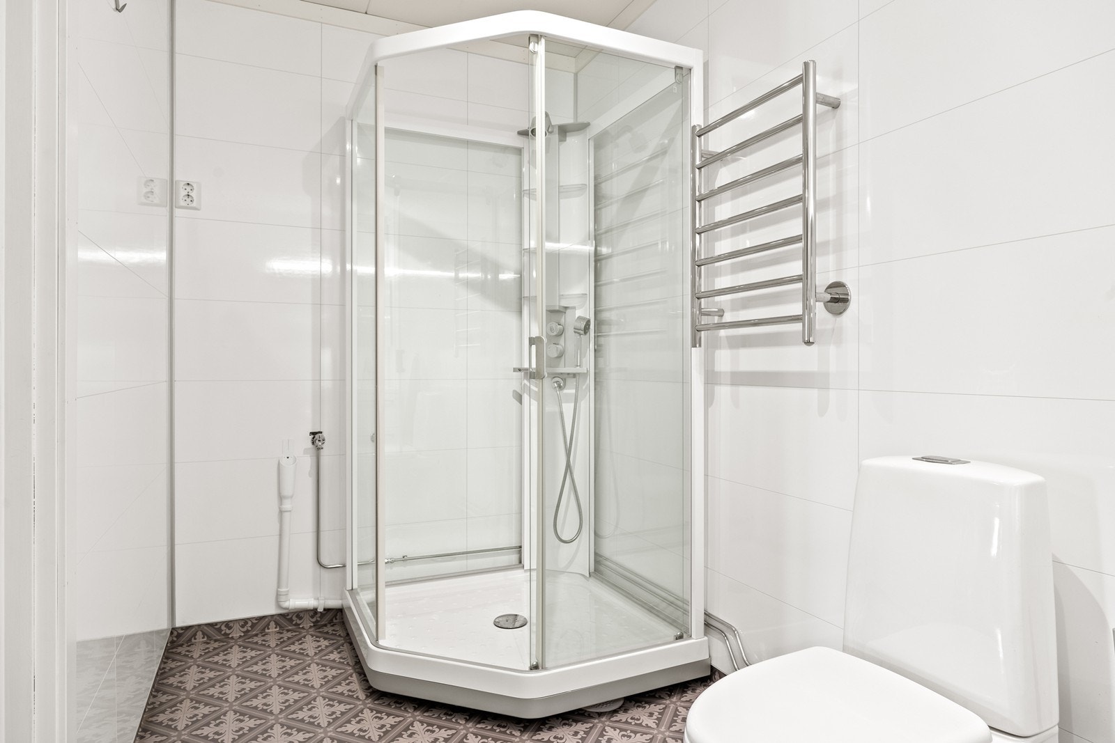 Rommet er innredet med hvit baderomsinnredning med skuffer for oppbevaring og heldekkende servant. Over innredning er det speilsskap med belysning. Videre har badet toalett, dusjkabinett og opplegg for vaskemaskin. Galleribilde