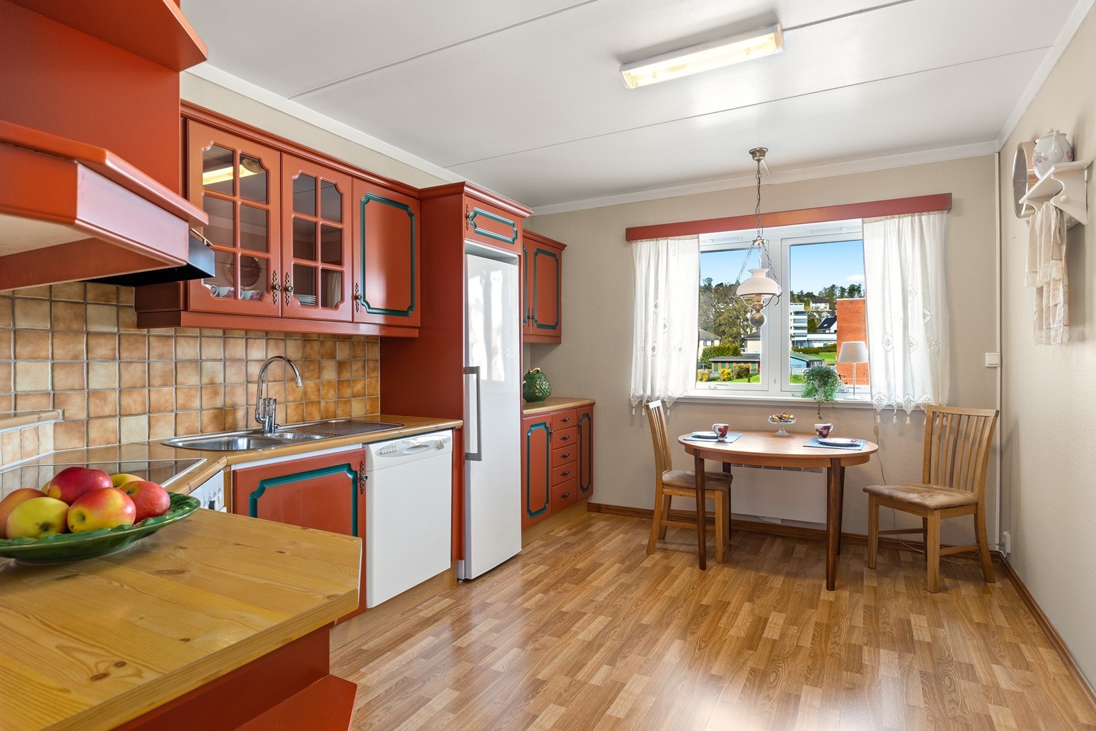 Kjøkkenet er et ekte blikkfang med sine profilerte fronter malt i en levende rød farge, elegant komplementert av grønne detaljer. Galleribilde