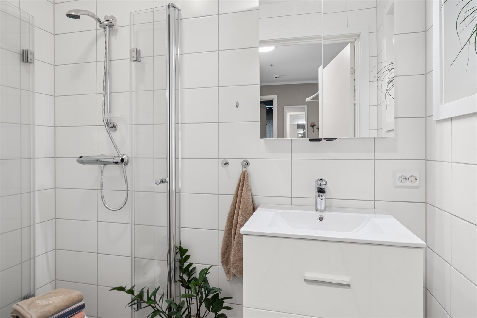 Bad med fliser på gulv og vegger, innredet med toalett, dusjhjørne og innredning med nedfelt servant. Galleribilde