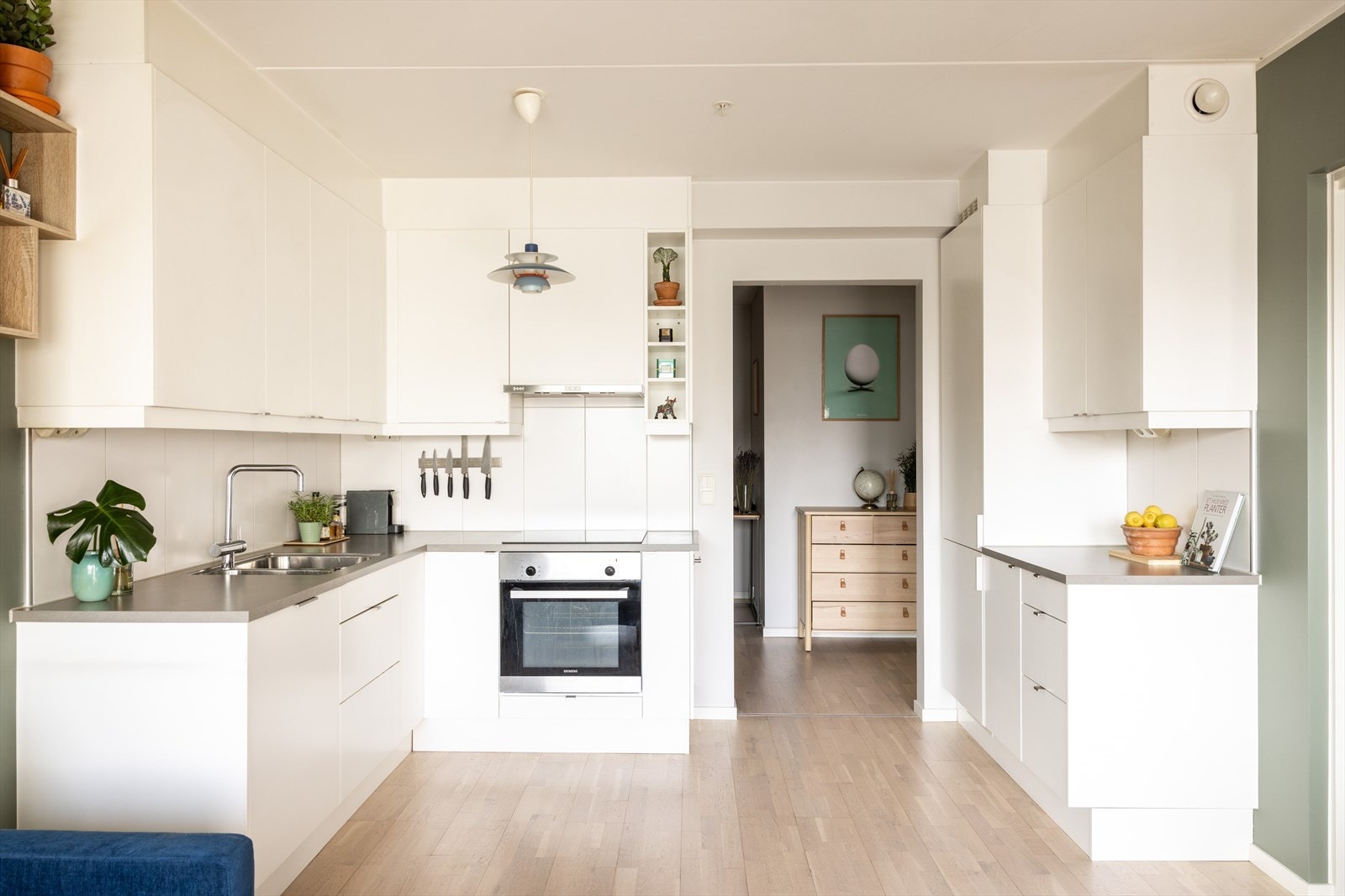 Stilrent kjøkken bestående av hvite, glatte fronter og benkeplate av laminat med nedfelt vaskekum. Galleribilde