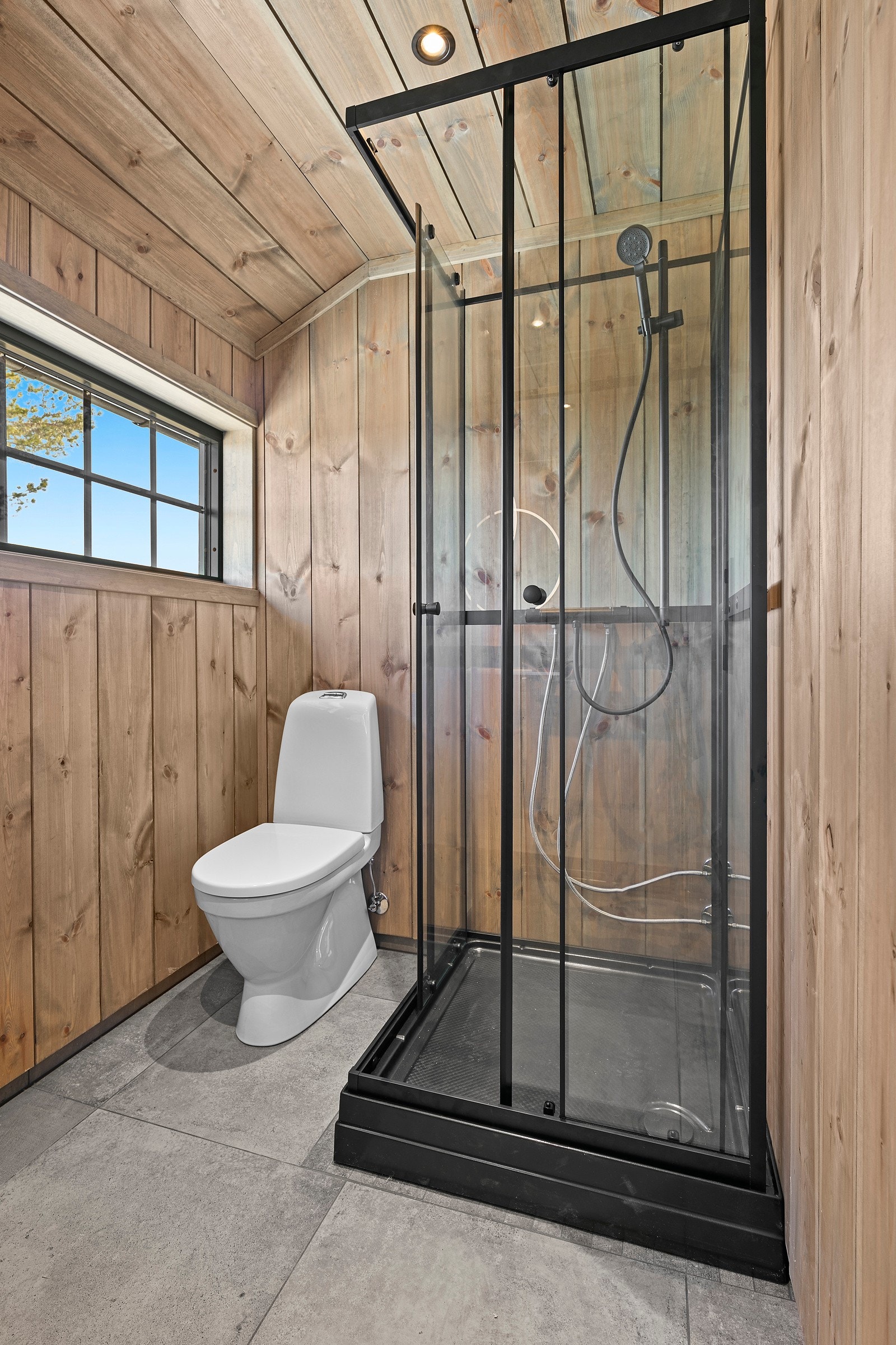 Badet har dusjkabinett, toalett, servant med innredning og speil med belysning Galleribilde