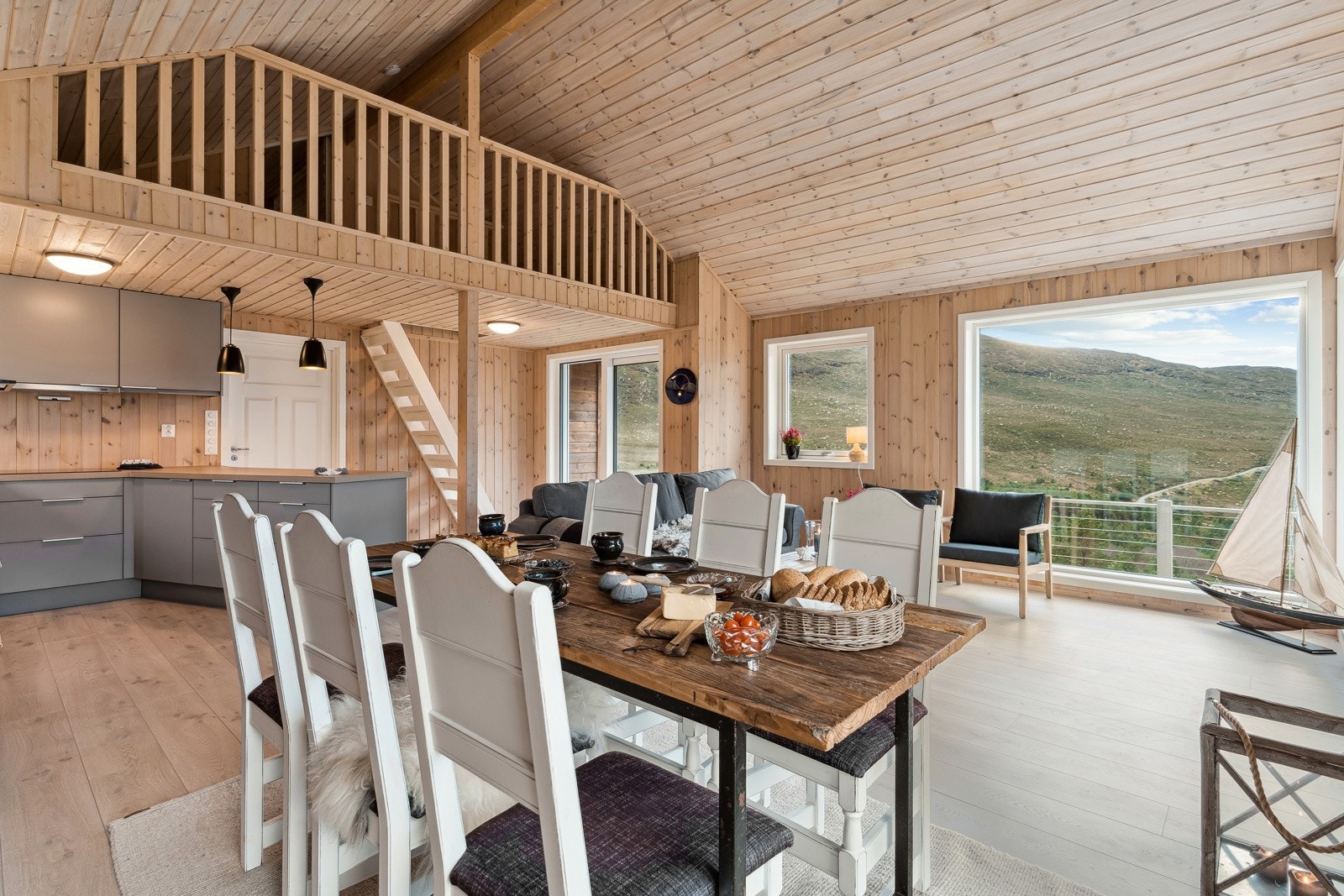 Kjøkken og stove i open løysing utgjer eit sosialt og hyggjeleg allrom. Hems med mesanin mot opphaldsrommet gir ei lun og god hyttekjensle. Galleribilde