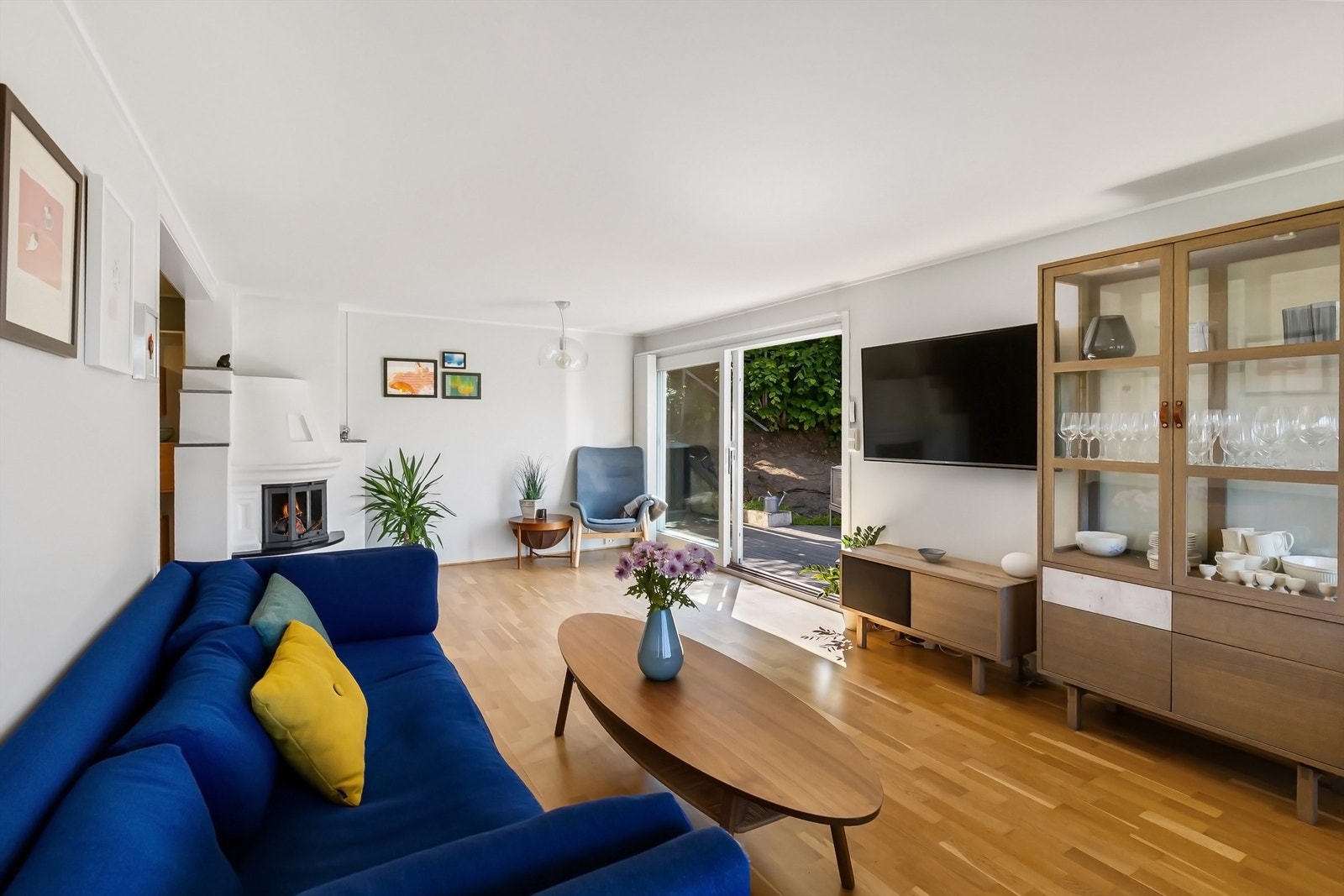 Stor og lys stue med peis og utgang til hage og terrasse Galleribilde