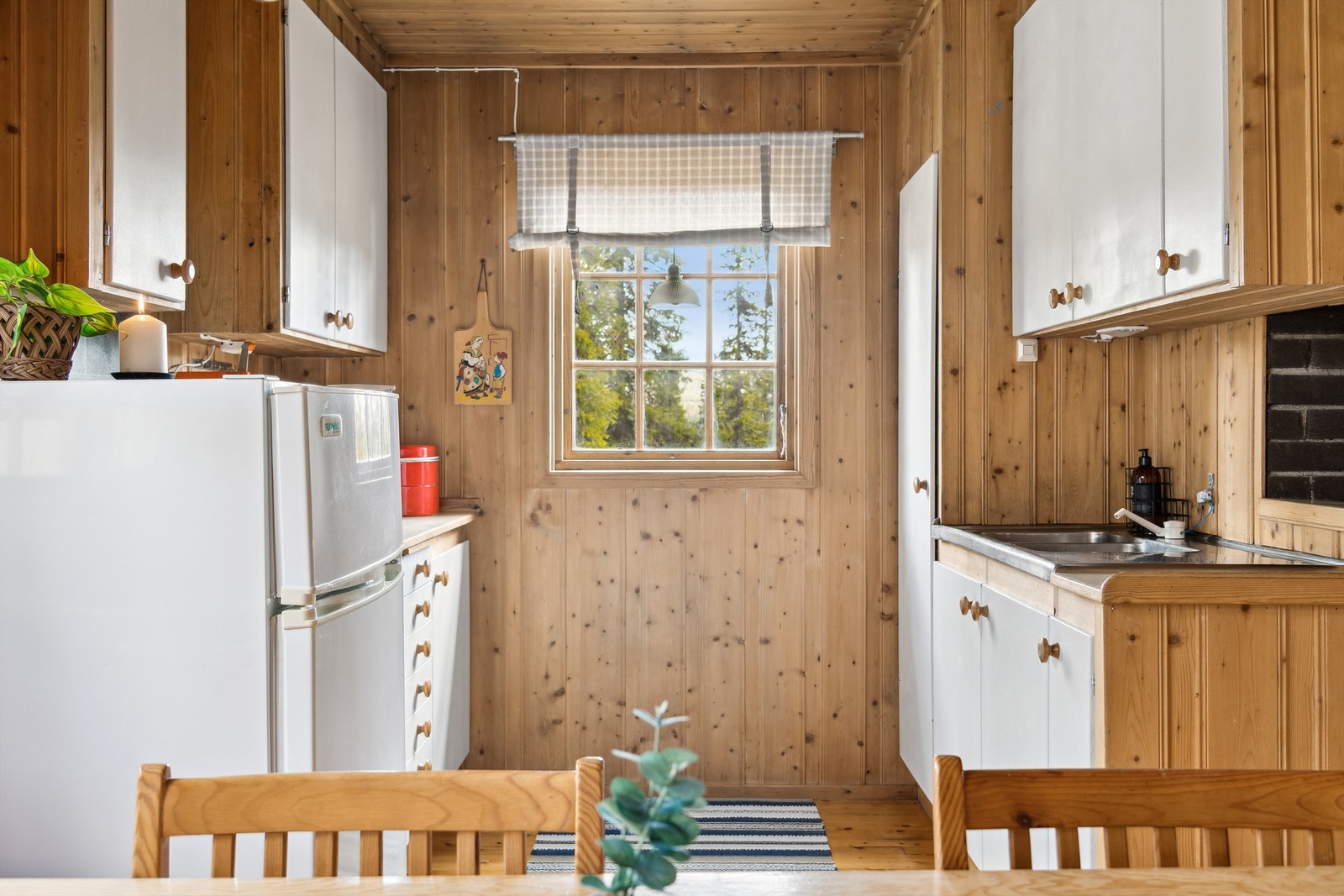 Kjøkken med innredning med hvitmalte fronter. Åpen løsning for komfyr og kjøl-/fryseskap Galleribilde