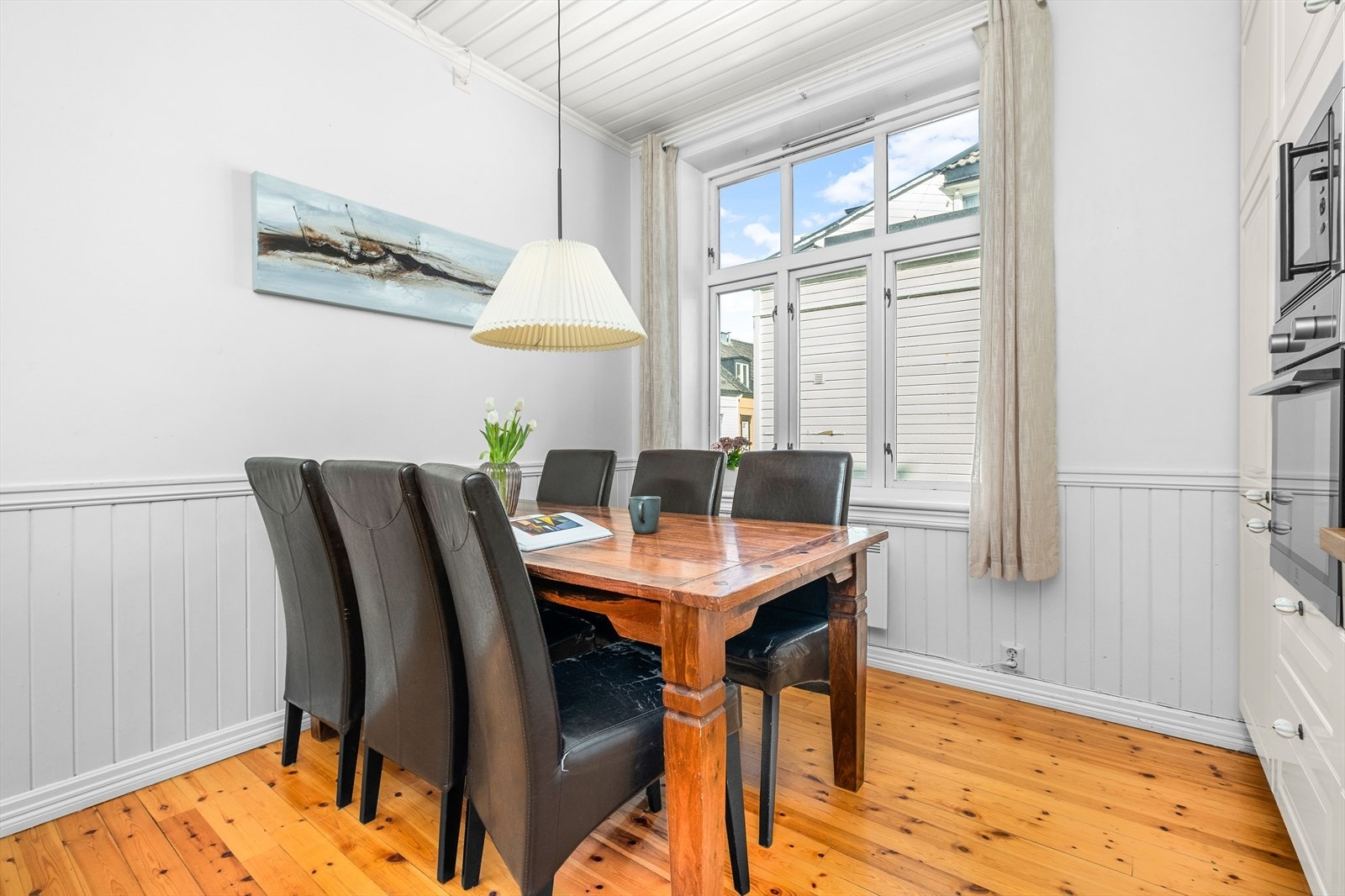 Romslig kjøkken med stort vindu som gir et herlig lysinnslipp ved frokostbordet Galleribilde