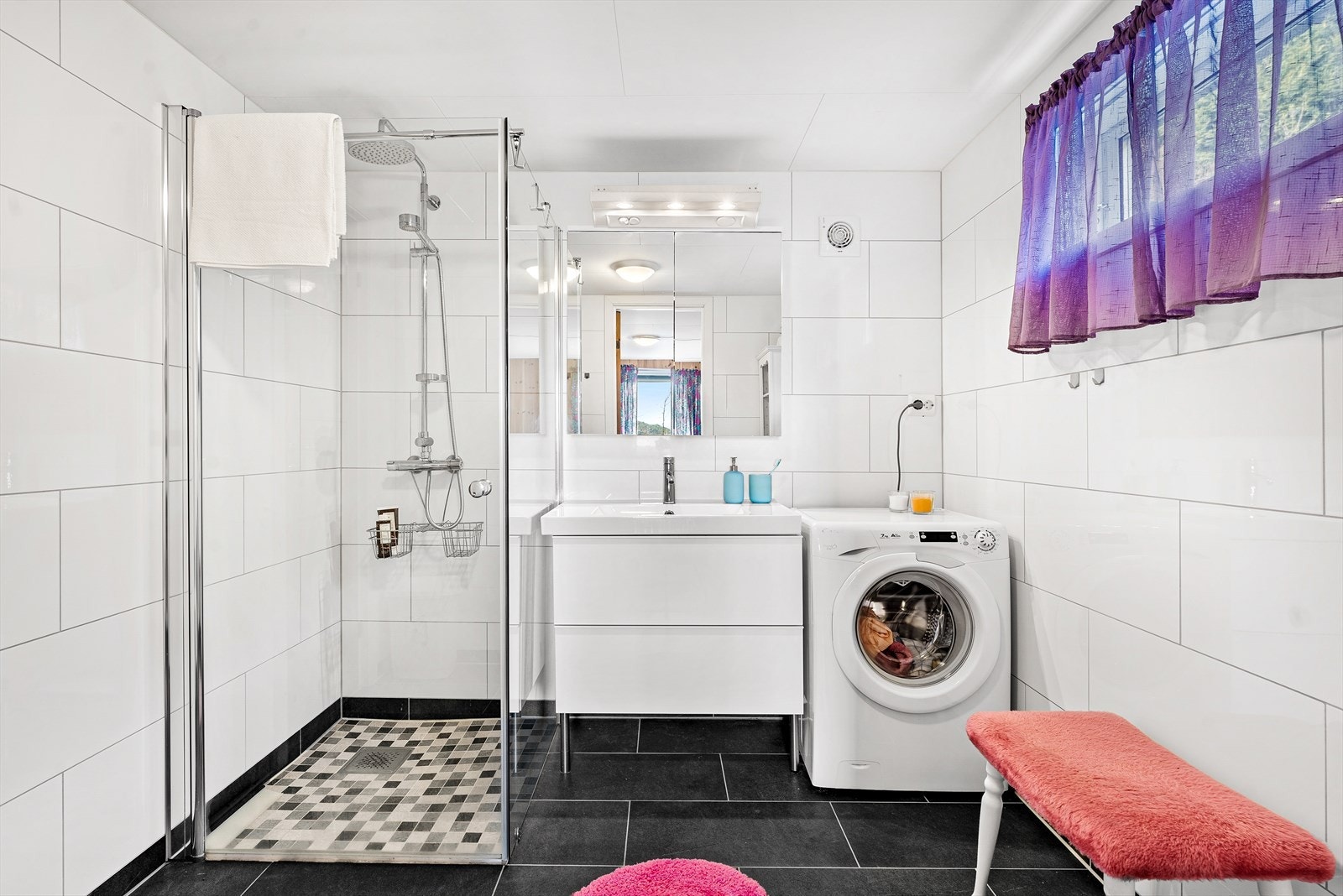 Her er det innredet med dusjhjørne med glassvegger, lekker innredning med vask og vaskemaskin. Galleribilde