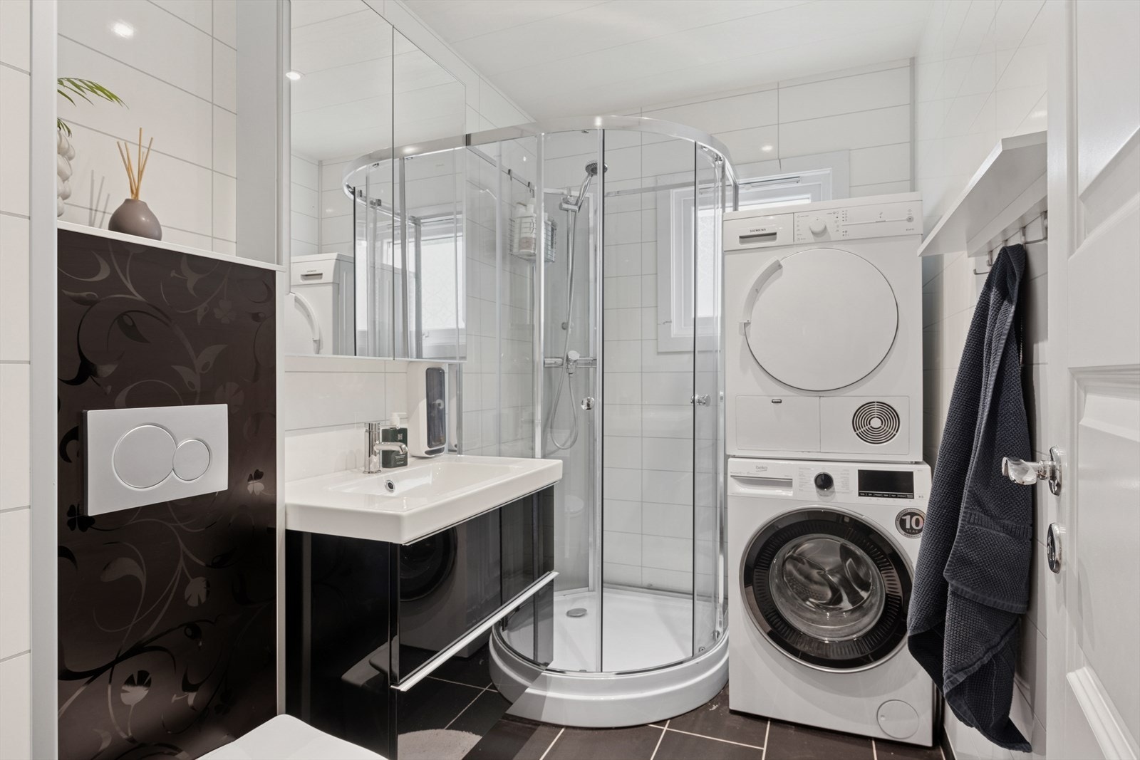 Delikat bad med flislagt gulv og varmekabler. Utstyrt med dusjkabinett, opplegg for vaskemaskin/tørketrommel, vegghengt wc og moderne baderomsinnredning. Galleribilde